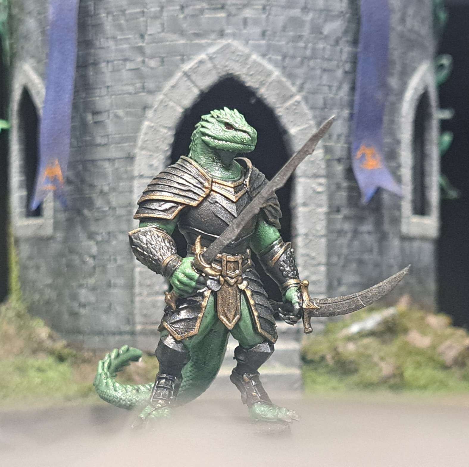 A detailed miniature figure of a lizard-like warrior in armor holding a sword and bow in front of a medieval stone castle backdrop.