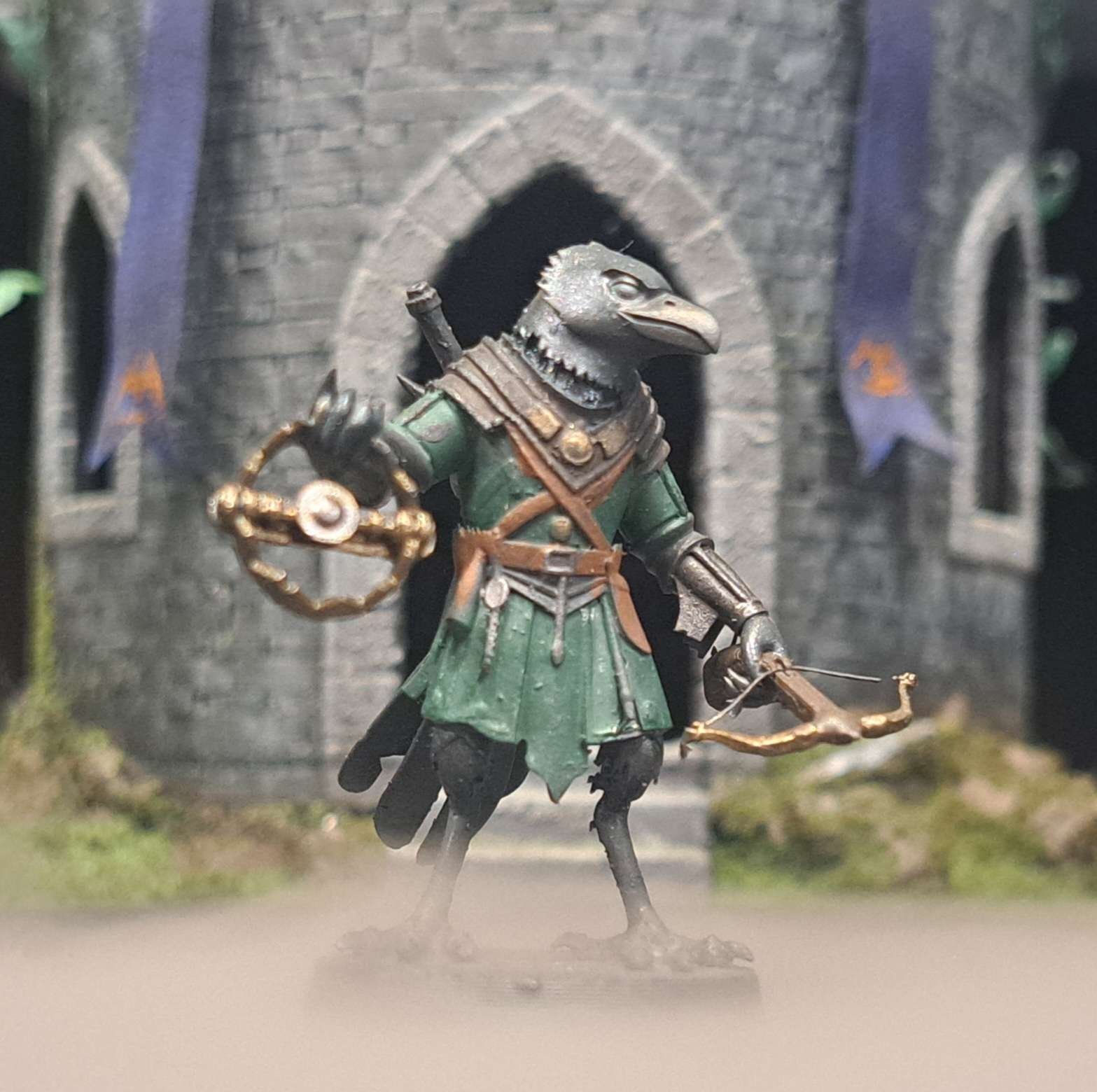 A miniature figurine of a humanoid bird dressed in medieval armor, holding a bow, standing in front of a castle backdrop with purple banners.