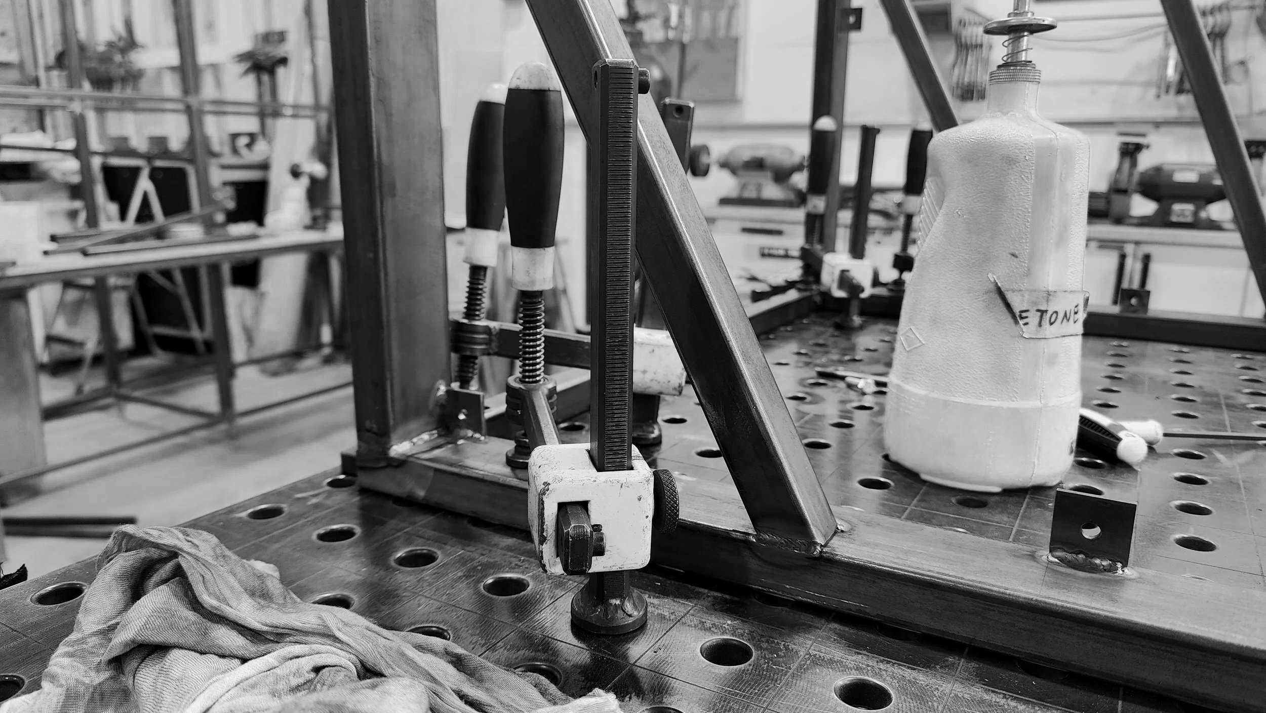 Workshop workspace with clamps, a workbench, and a plastic bottle labeled 'tone'.