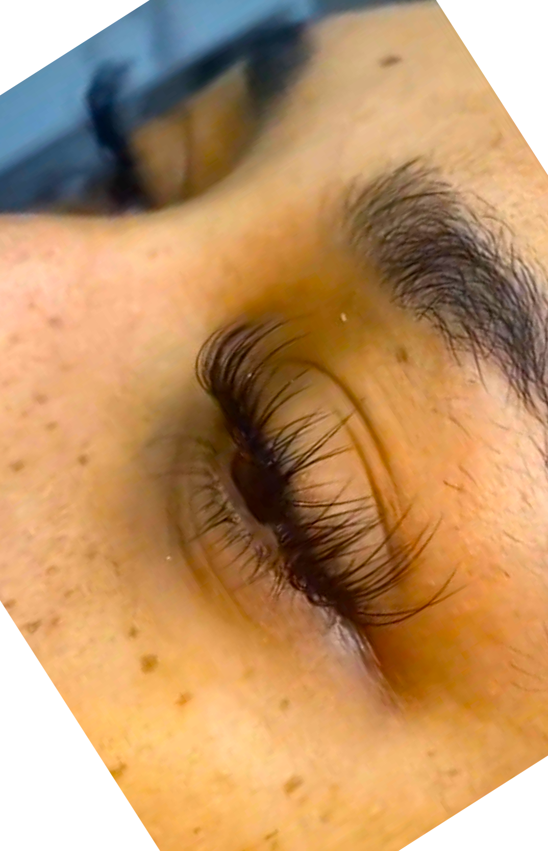 Close-up of a person's face focusing on closed eye with long eyelashes and thick eyebrow.