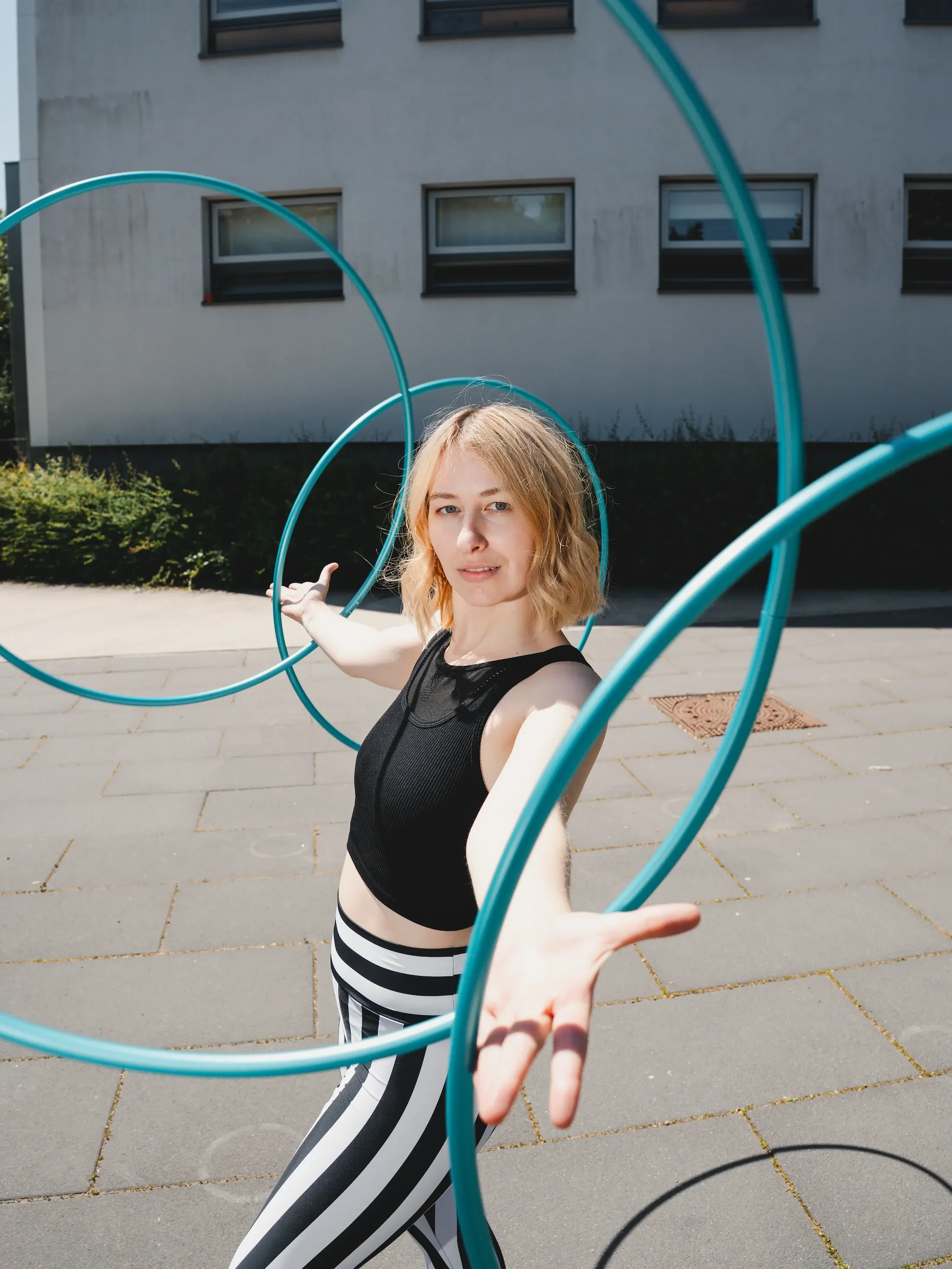 Hula-Hoop-Artistin Fabia posiert mit vier blauen Hula-Hoop-Reifen in den Händen