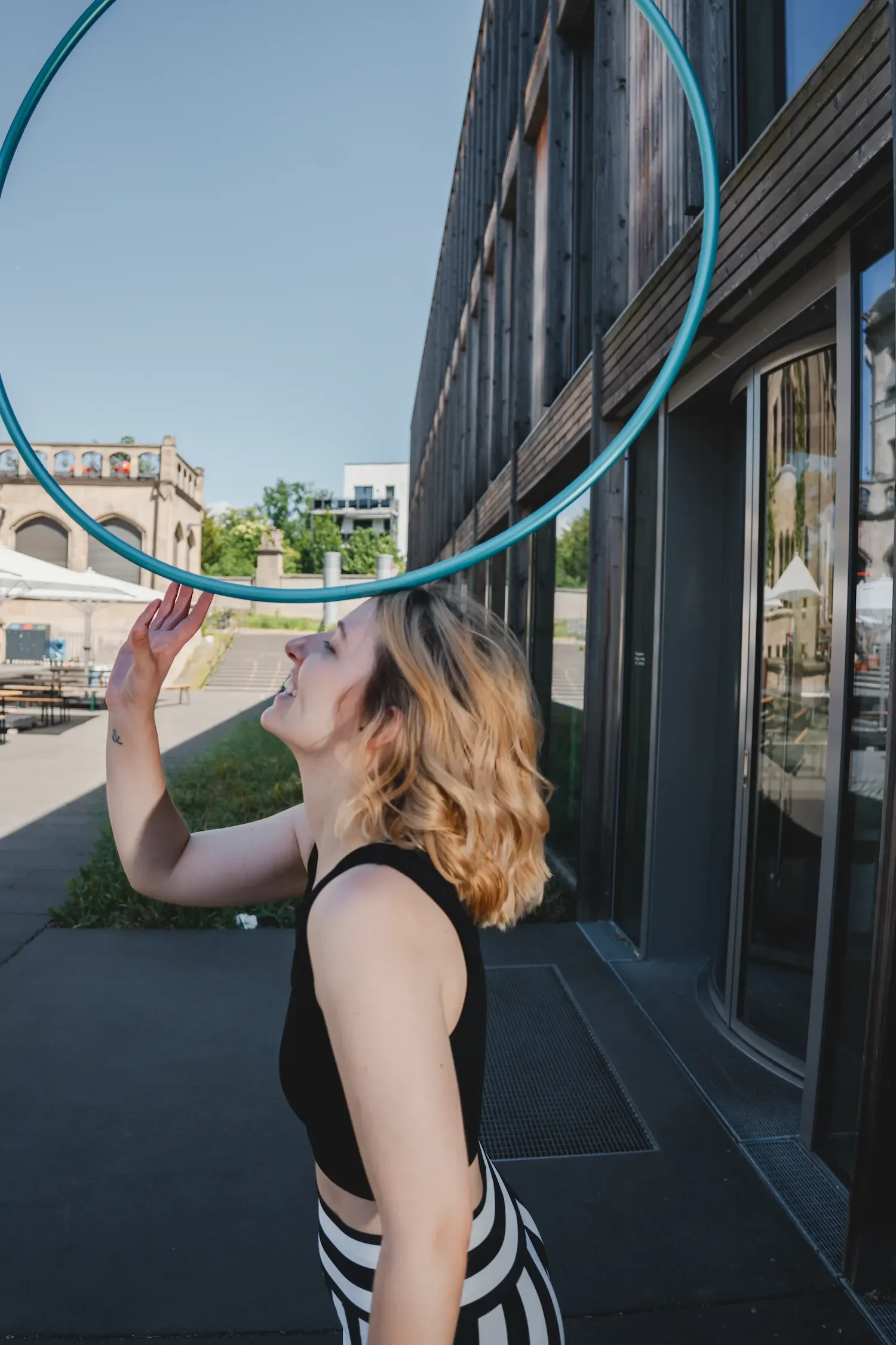 Hula-Hoop-Trainerin Fabia lacht und balanciert einen Hula-Hoop-Reifen auf dem Kopf