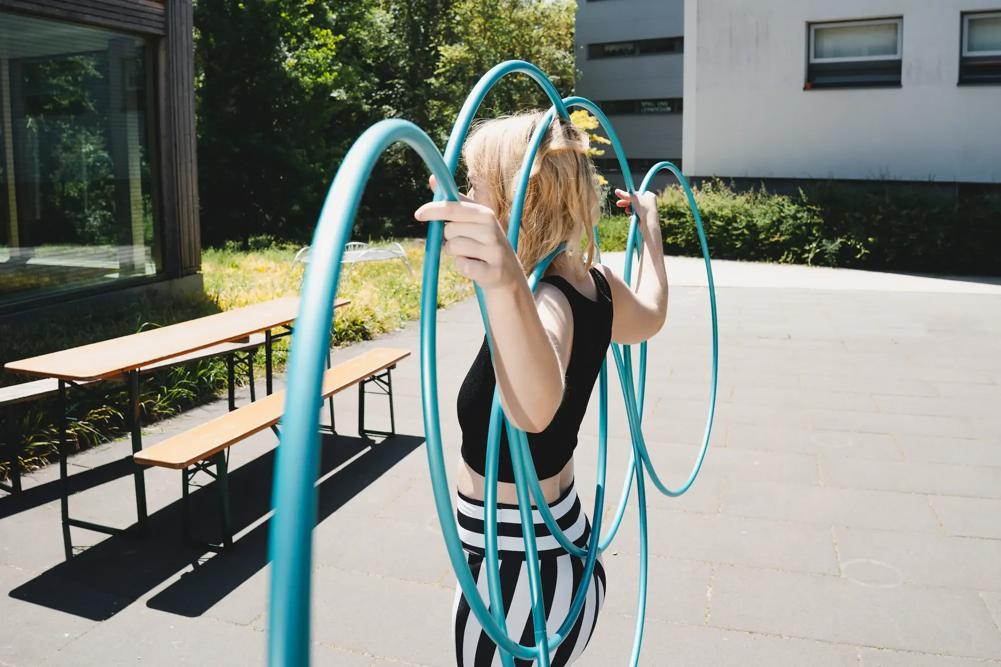 Hula-Hoop-Trainerin Fabia hält vier blaue Reifen in einer Pose