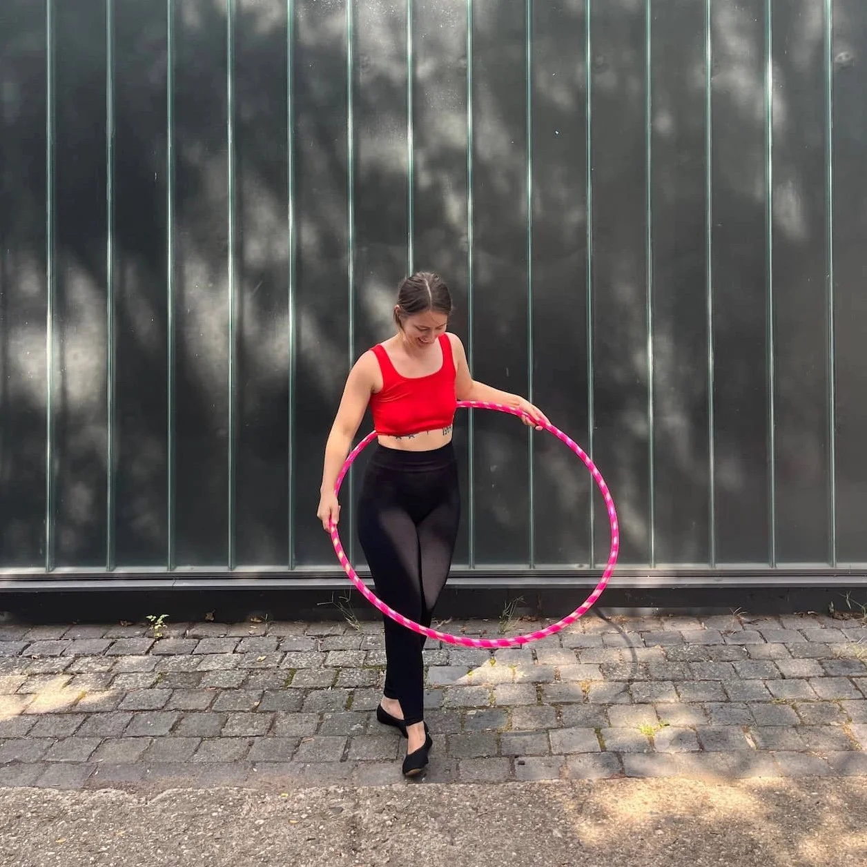 Hula-Hoop-Profi Fabia mit einem pinken Hula-Hoop um den Bauch