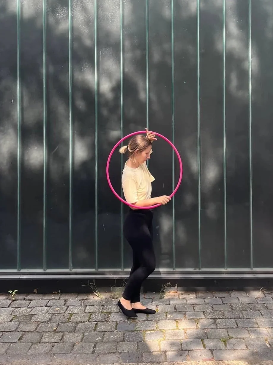 Hula-Hoop-Trainerin macht einen Hula-Hoop-Trick mit einem pinken Reifen