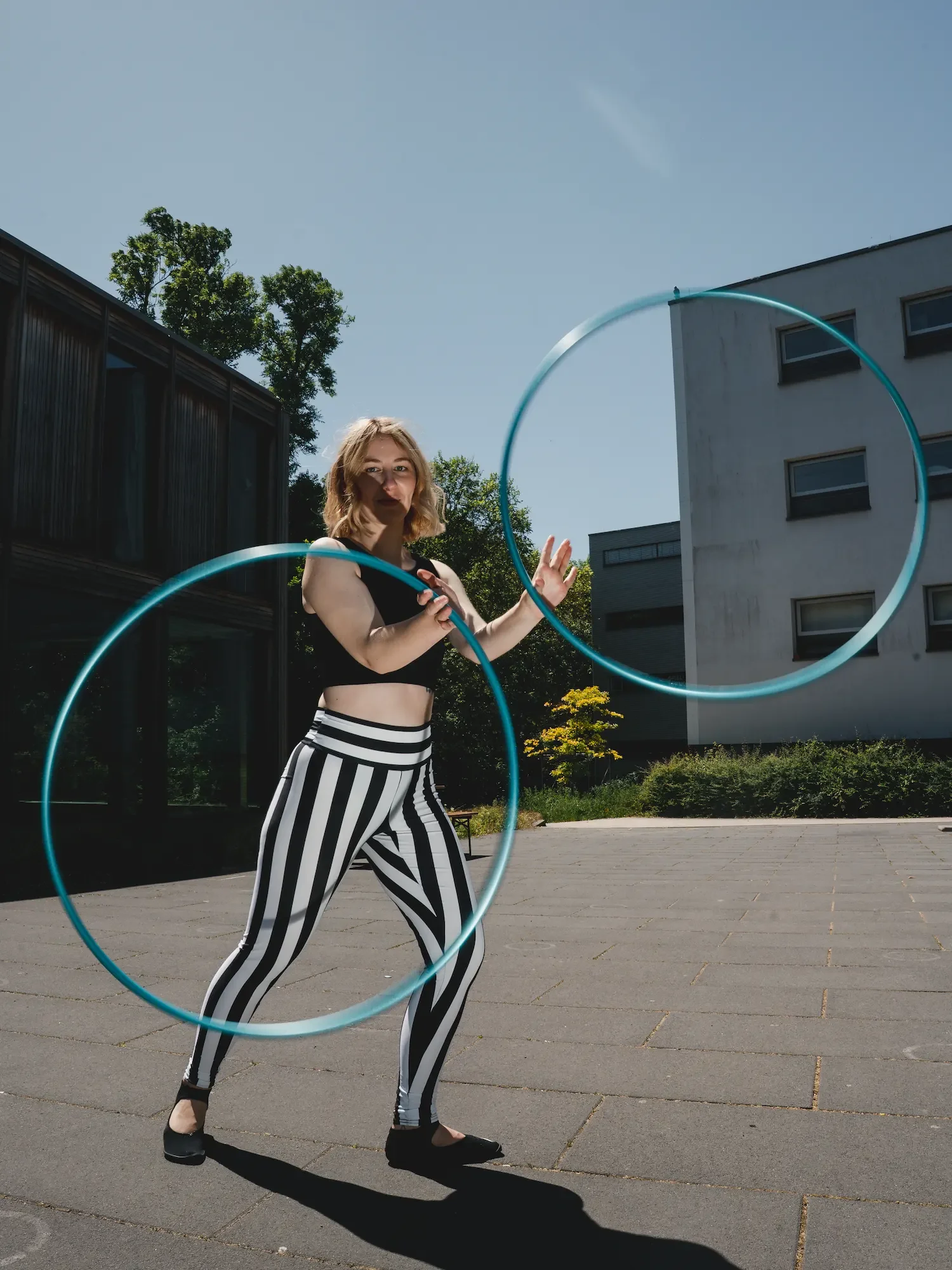 Zirkus-Artistin Fabia im Kostüm mit zwei Hula-Hoop-Reifen in Bewegung
