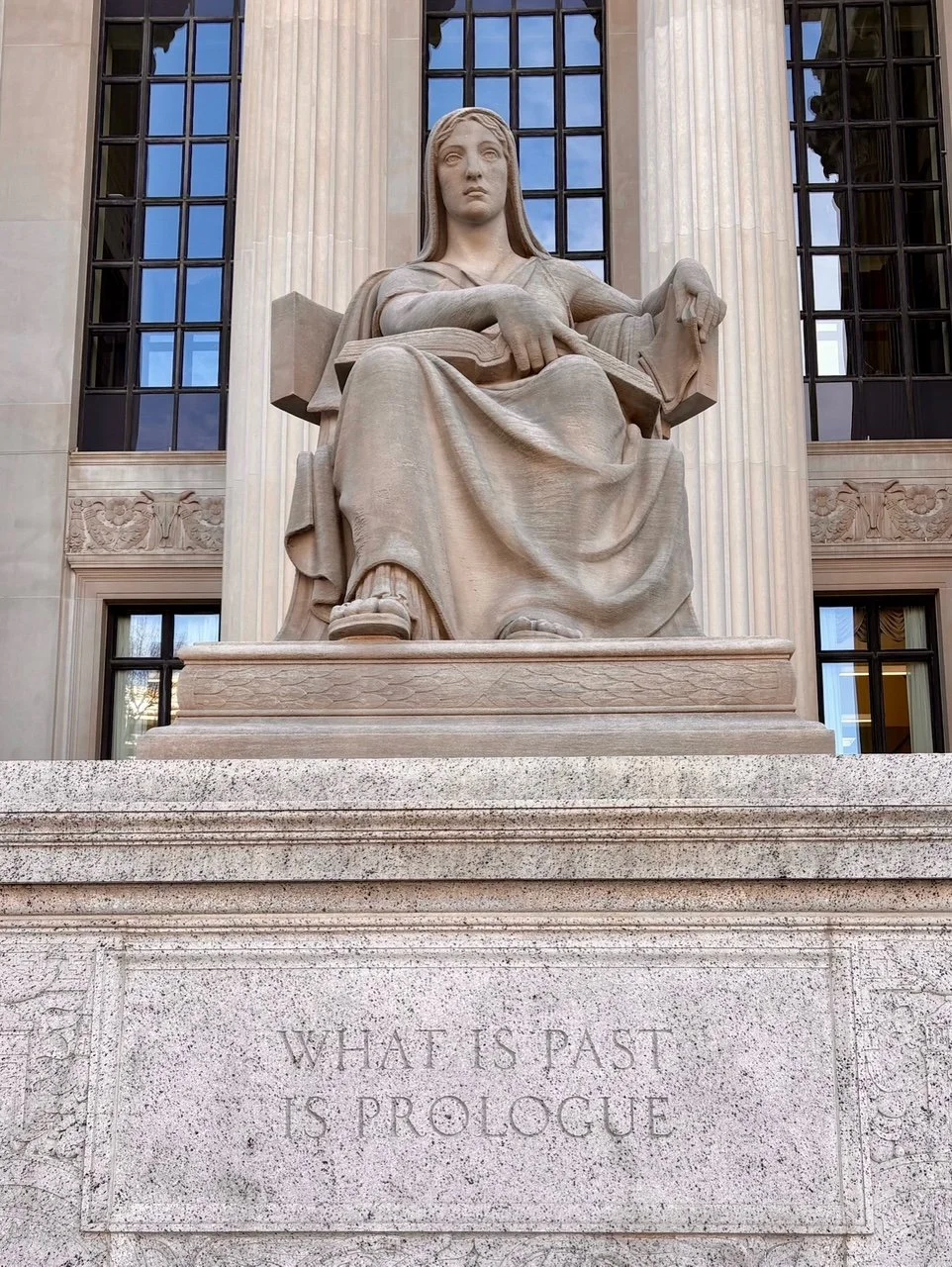 Statue of seated woman holding a book.   The statue is located in front of the National Archives in DC. and is entitled "Future."   Robert Aiken was the sculpture.  On the base of the status, the words "The Past is Prologue" are engraved .