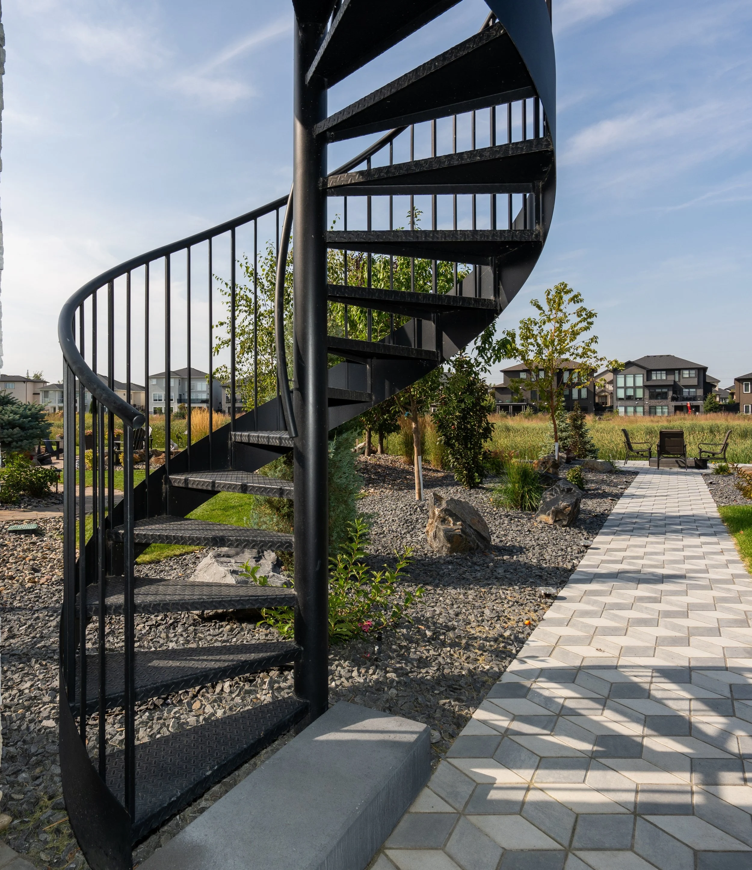 Custom exterior metal spiral staircase installed at a Winnipeg residential property by an architectural metalwork specialist.