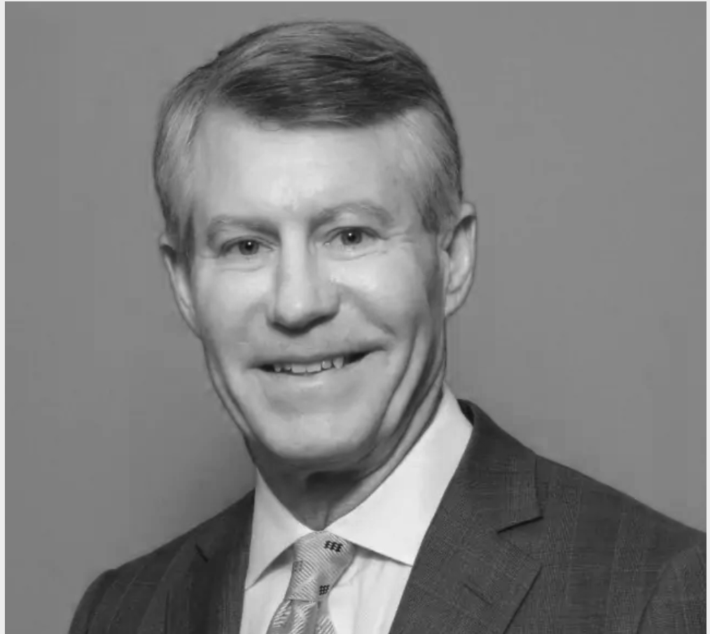 Black and white headshot of Stephen W. Perkins, MD, in a suit, smiling, with neatly styled hair, against a plain background.