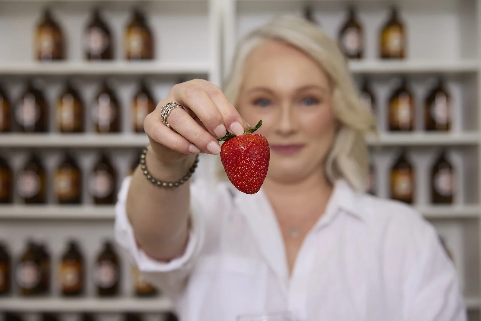 Clinical nutrition practitioner Melanie Makris holding fresh strawberry representing personalised nutrition care at Paradigm Nutrition Bendigo Victoria