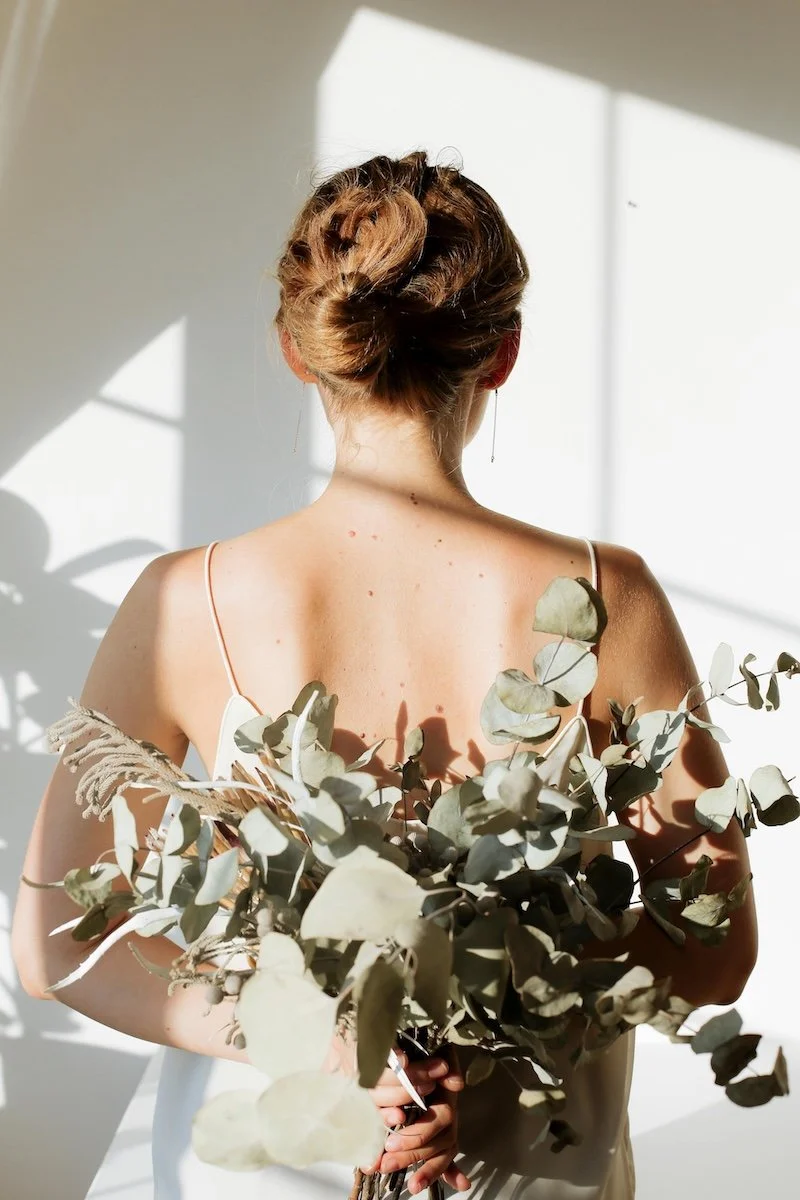 Woman holding eucalyptus branches symbolising natural hormone balance and menopause support through clinical nutrition at Paradigm Nutrition Bendigo Victoria