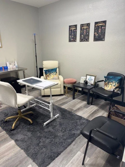 Medical examination room with chairs, a small table, and medical supplies on a side table.