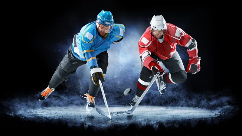 Two ice hockey players in blue and red jerseys competing for the puck on ice.