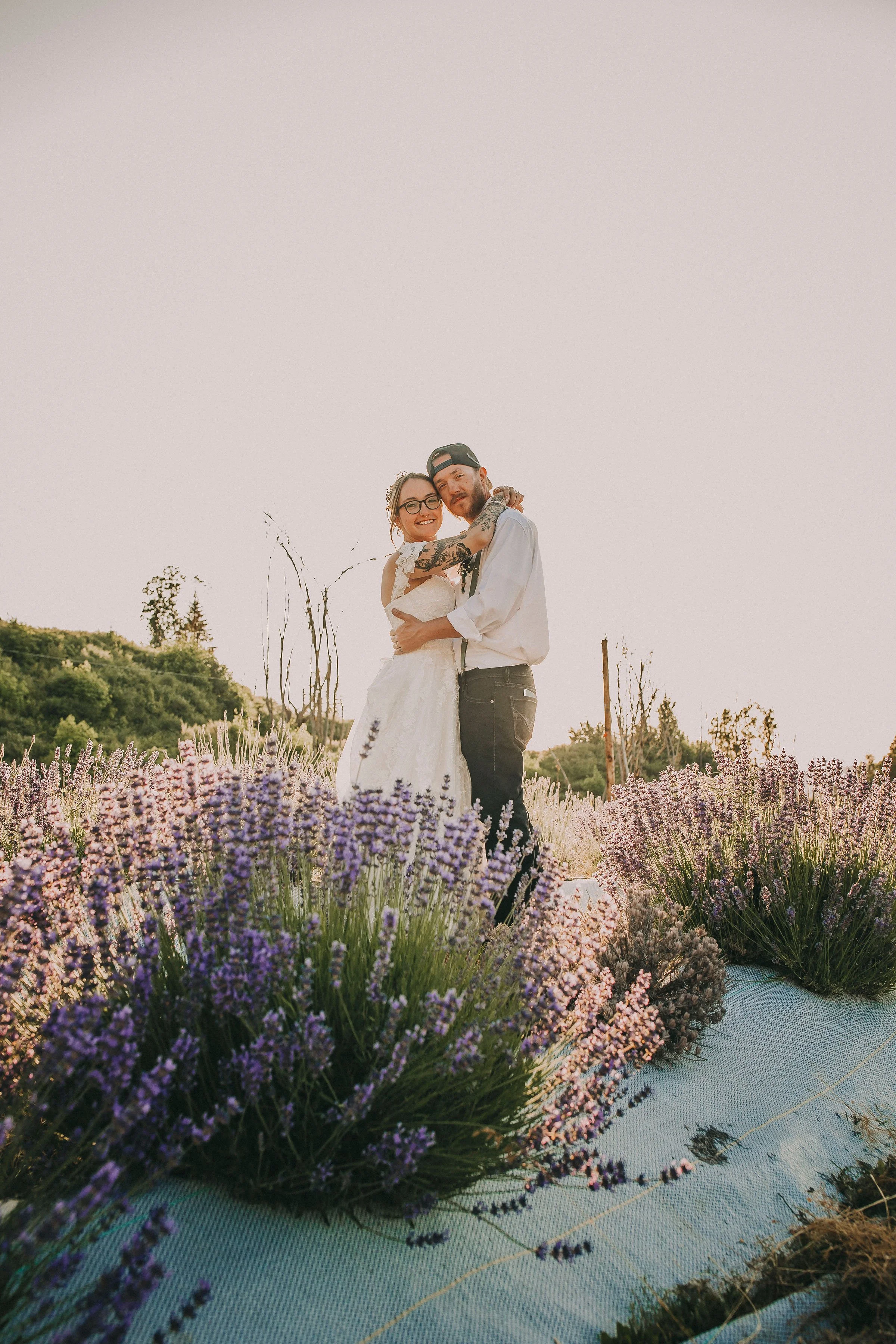 A couple embracing each other in a field of lavender flowers during sunset.