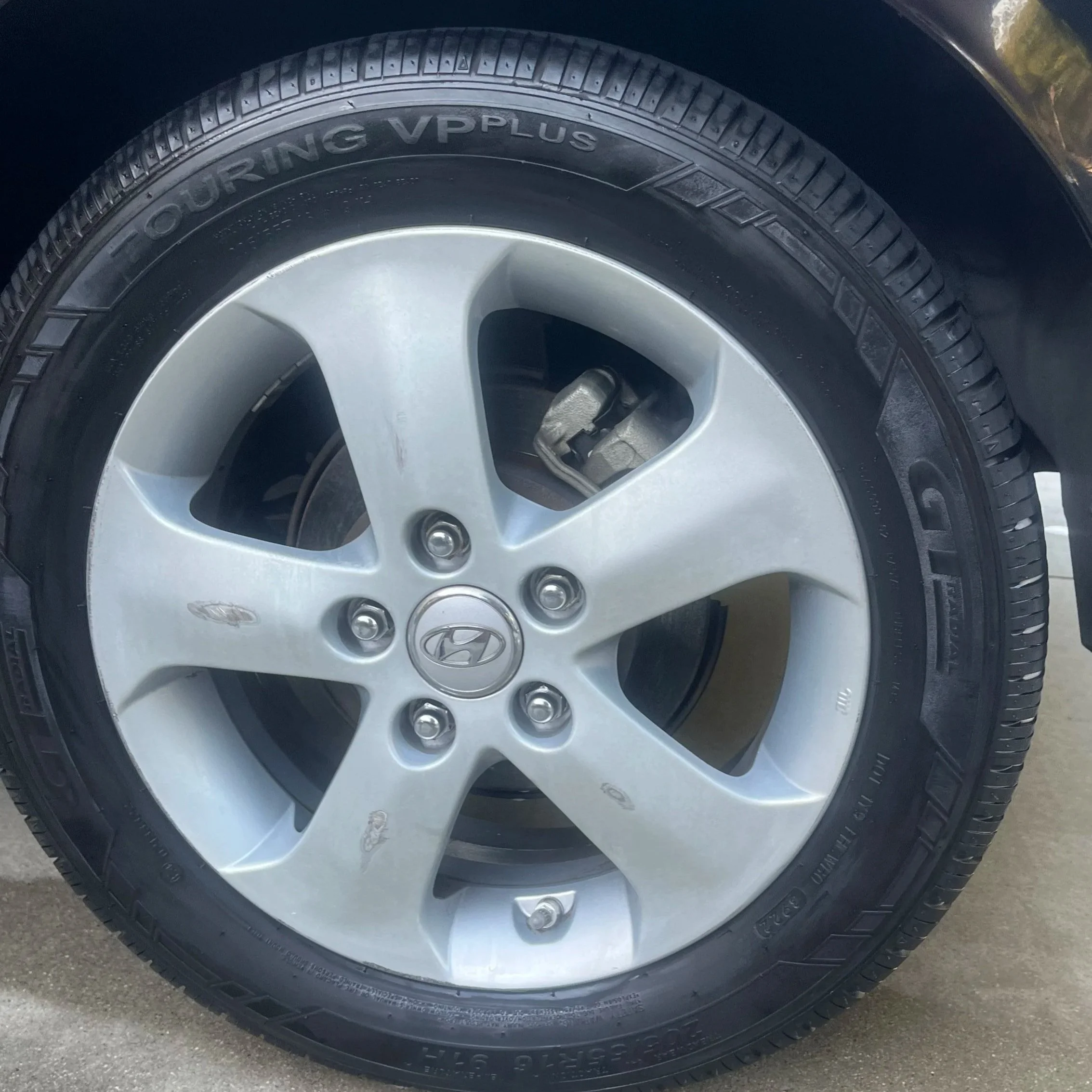 Close-up of a car wheel with a silver alloy rim, Hyundai logo center cap, and a black tire with the brand "Nexen" and model "Roadian HP". After picture of a car tire during a detail in Torrey Del Mar, California.
