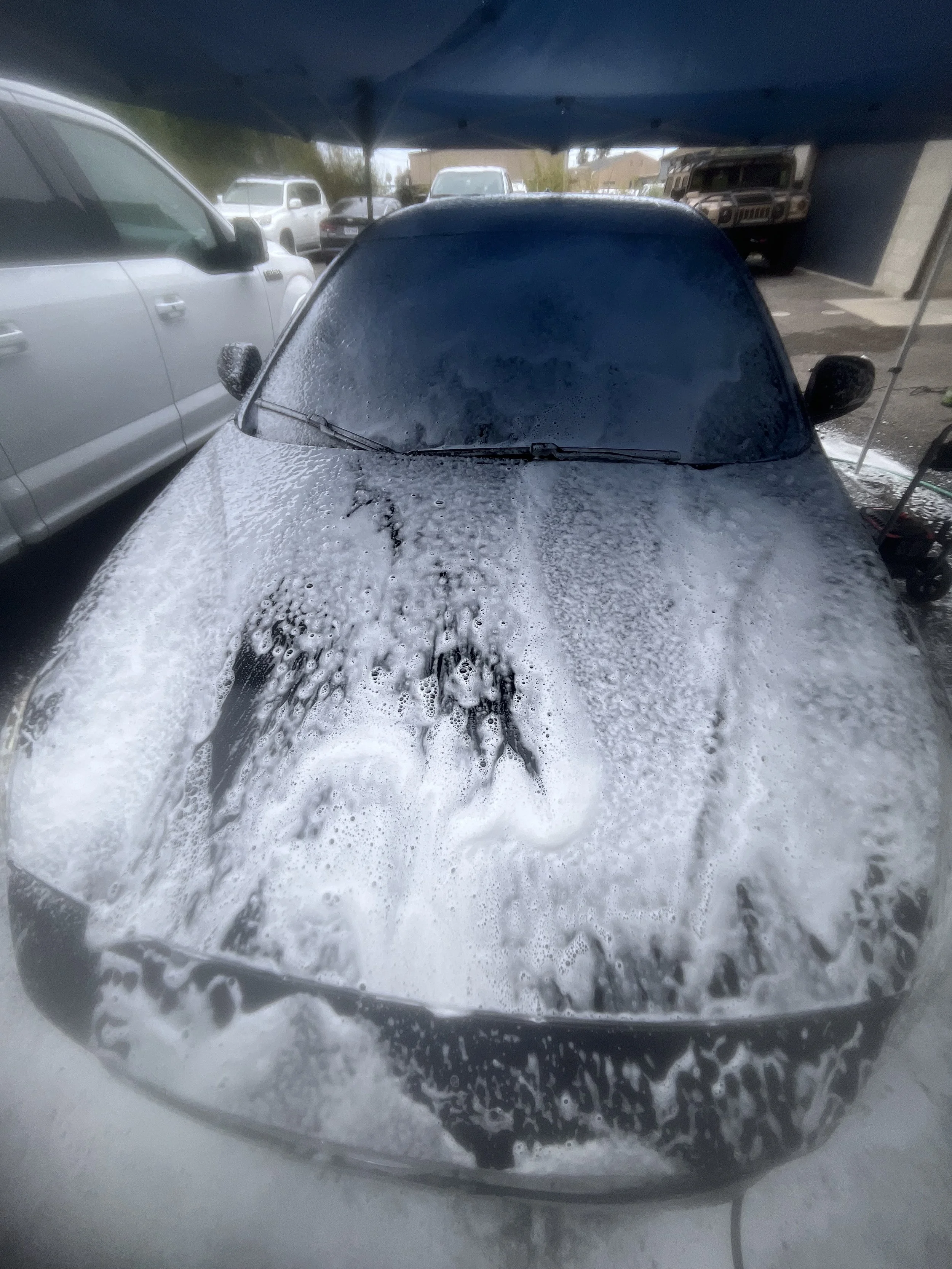 Car being washed with soap and foam on the hood and windshield. A photo during an exterior detail in Del Mar, San Diego.