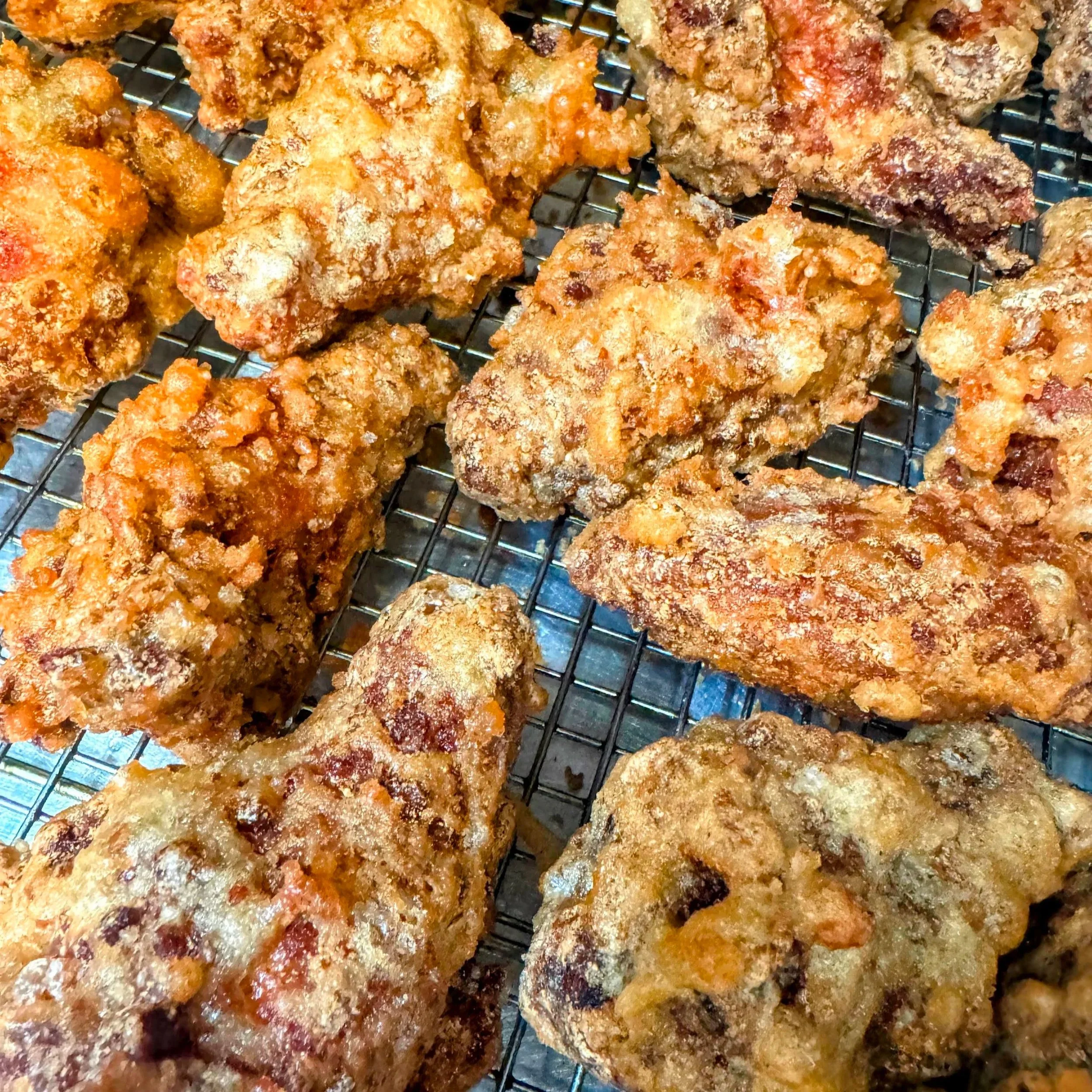 Fried chicken drumsticks and wings on a wire rack.