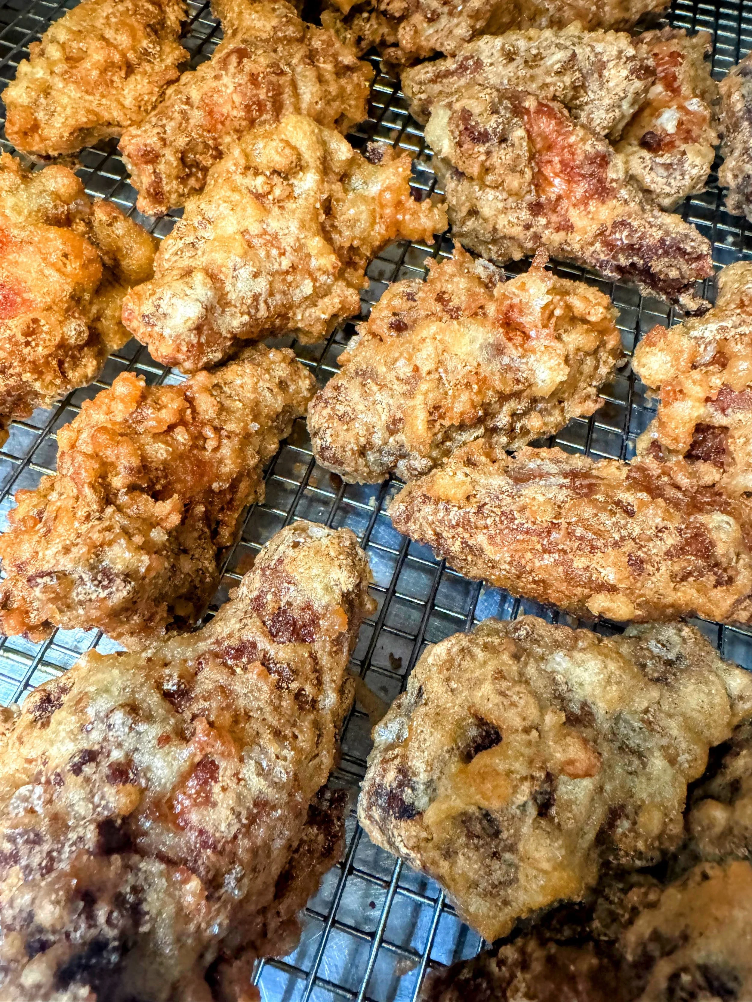 Assorted pieces of fried chicken cooling on a wire rack.