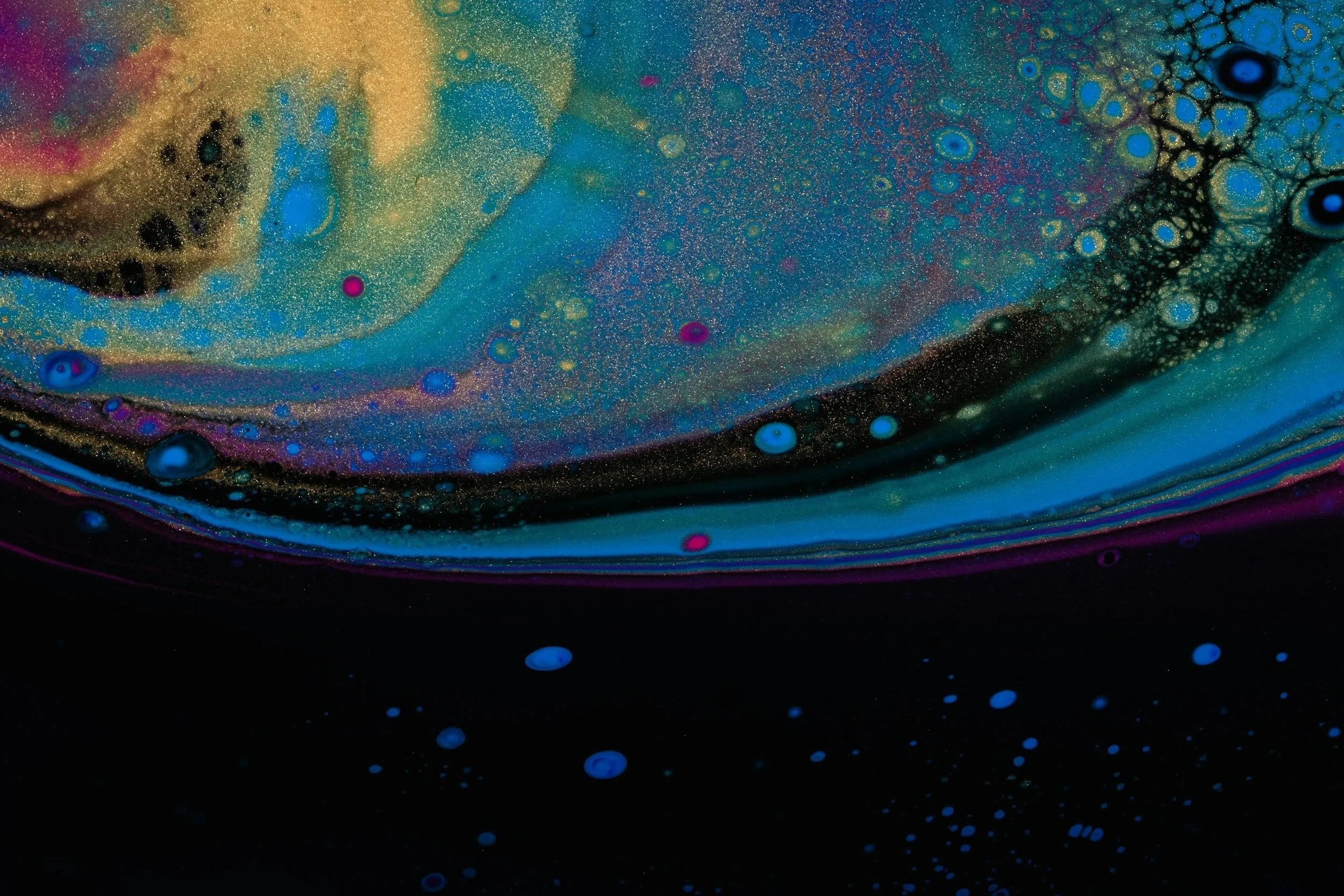 Abstract image of swirling colors including black, blue, pink, and gold, with speckled patterns and bubbles.