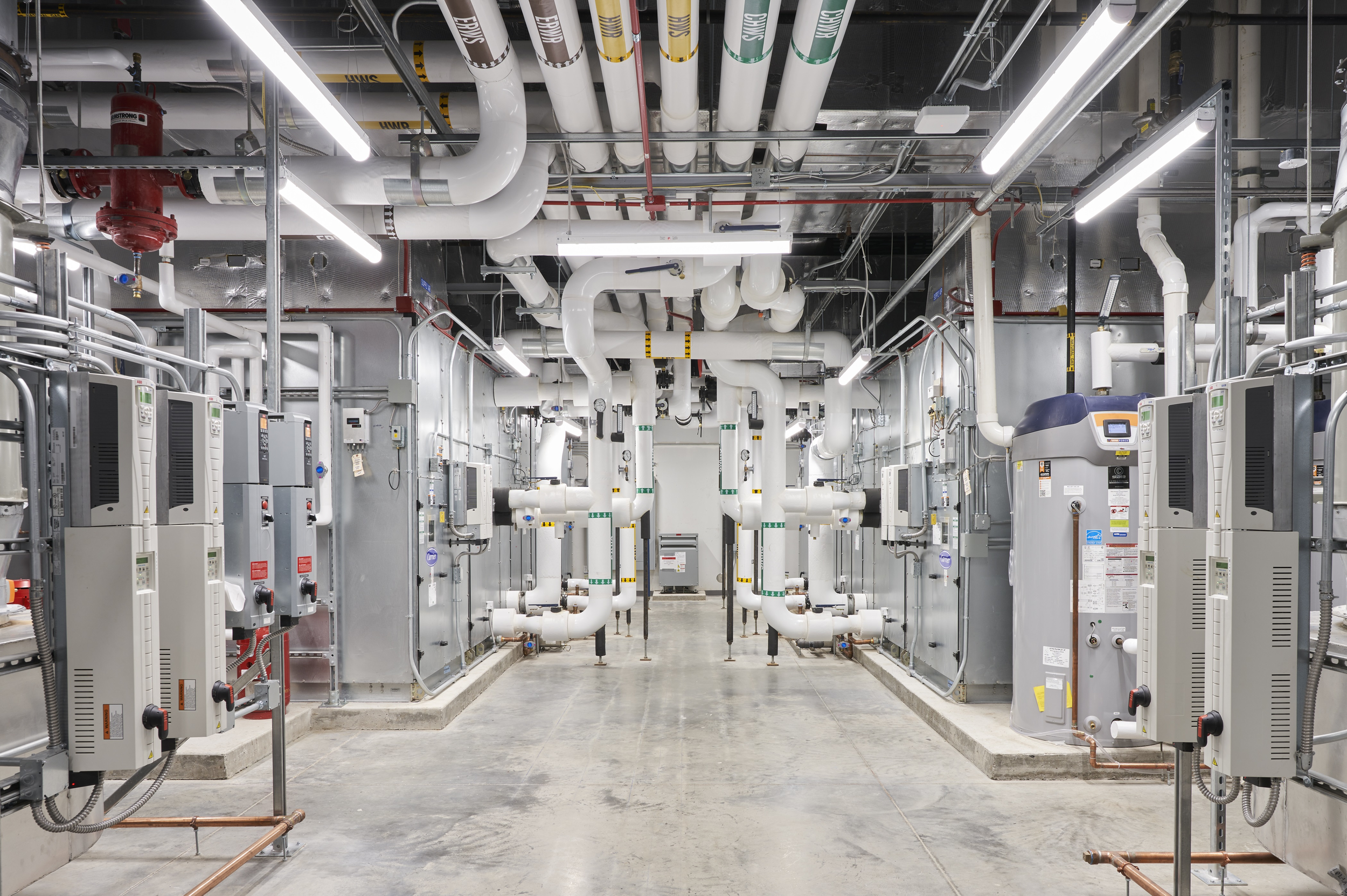 Industrial mechanical room with pipes, pumps, and electrical equipment.