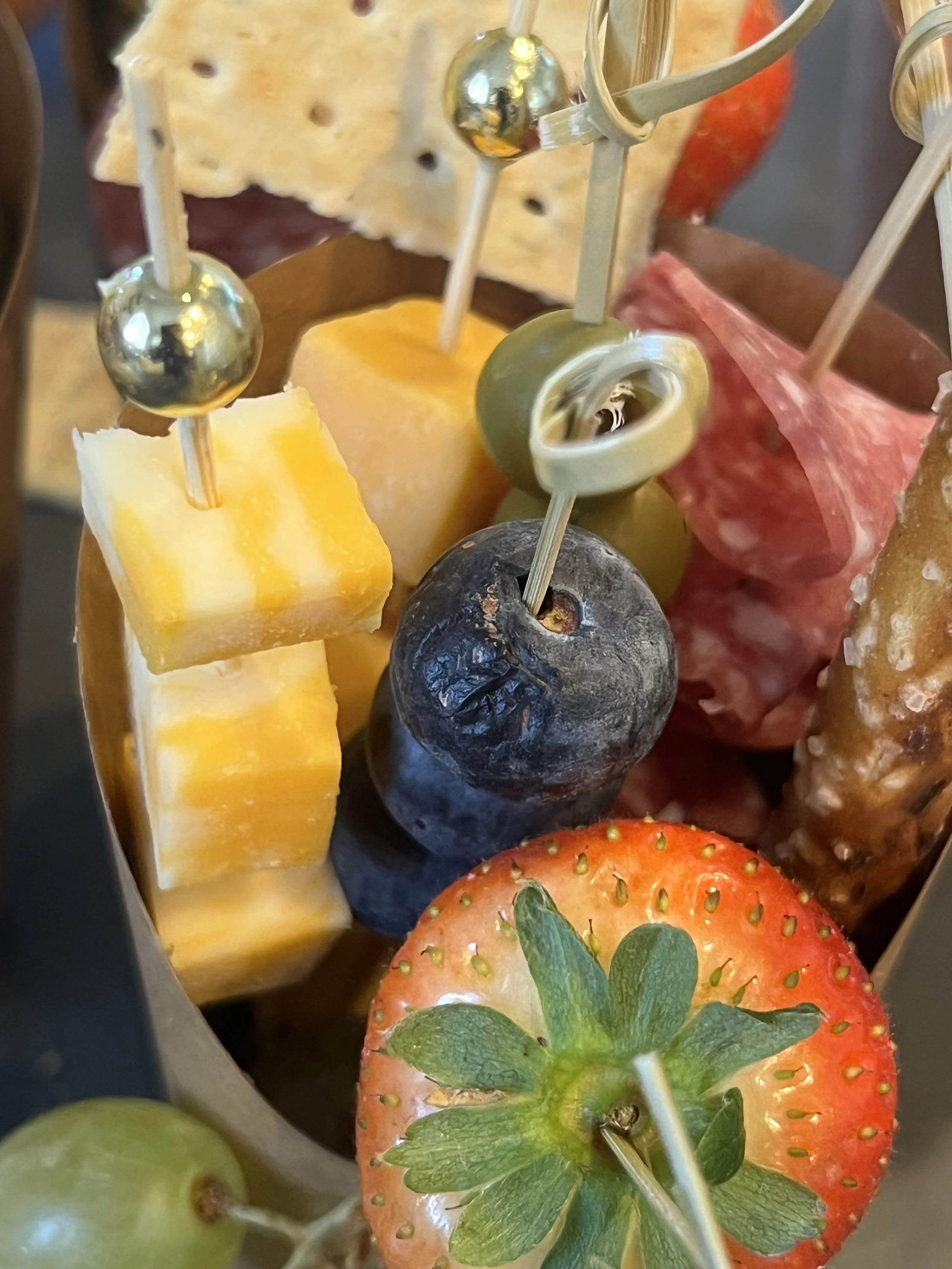 Close-up of assorted cheese and fruit skewers with a strawberry, blueberry, grape, and cheese cubes.