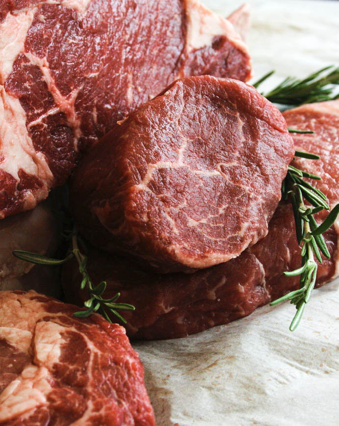 Close-up of raw beef steaks with sprigs of rosemary