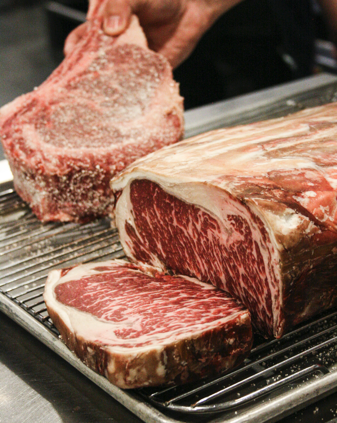 Close-up of raw, marbled beef cuts on a grill rack.