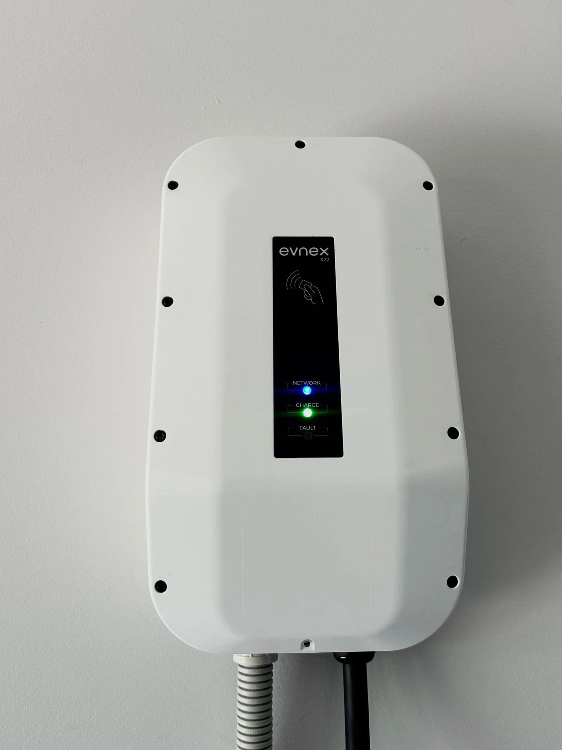 White evnex charging station mounted on a wall with indicator lights for network, charge, and fault.