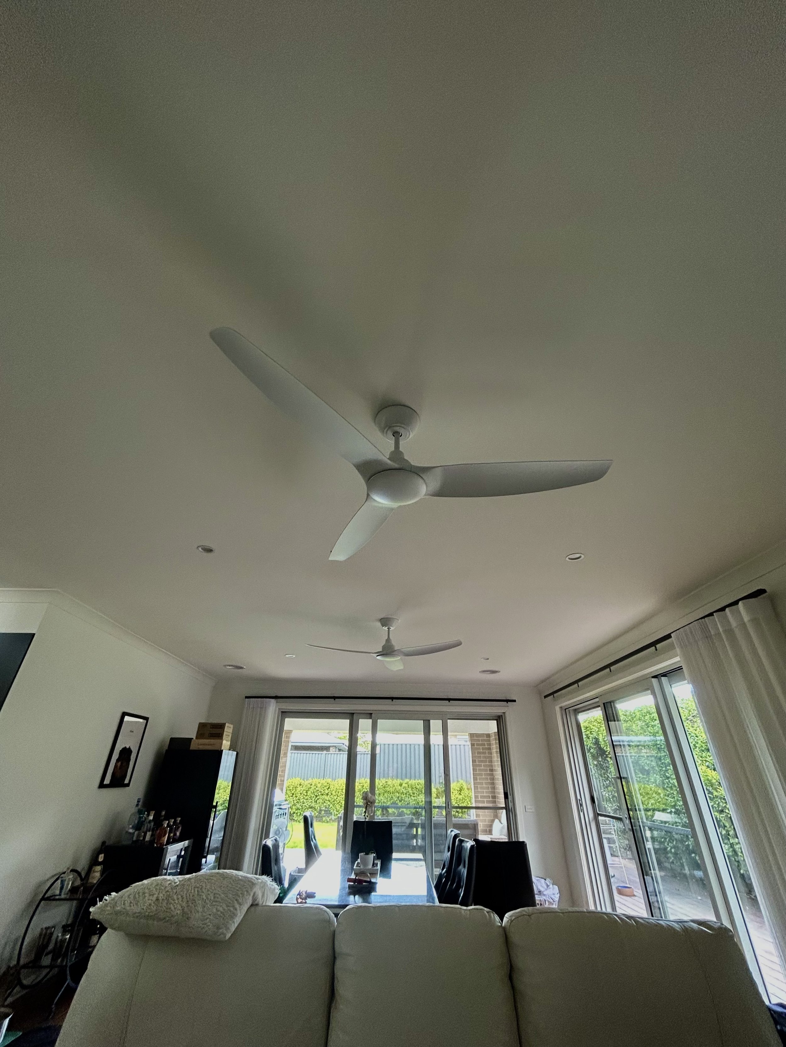 Living room with ceiling fans, sliding glass doors, and a dining table with chairs.