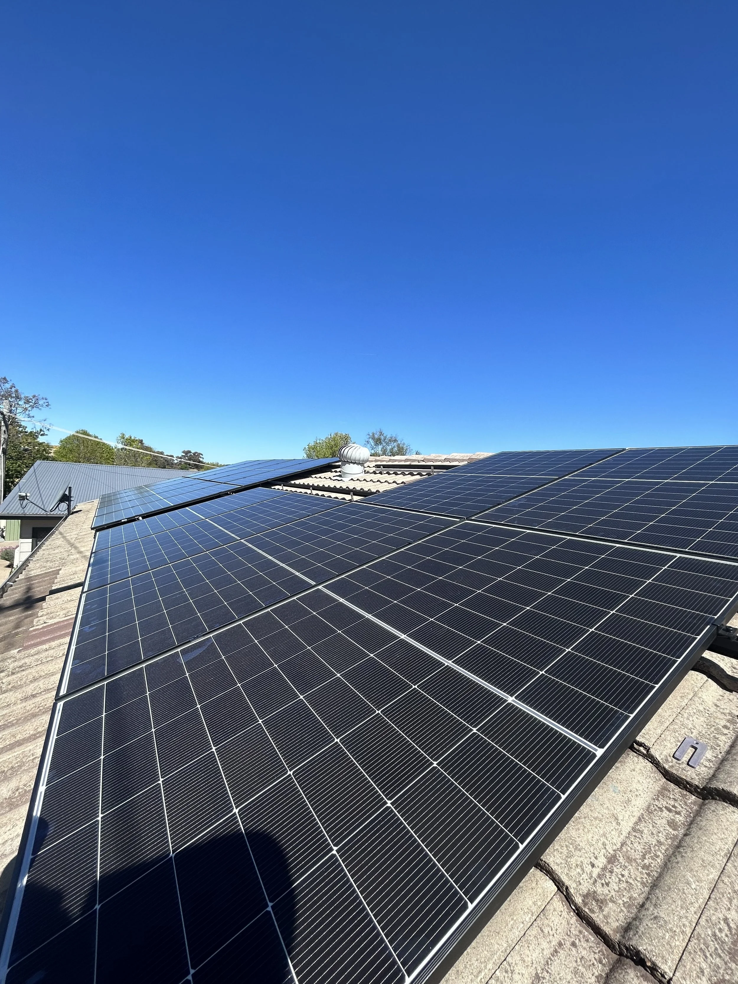 Solar panels installed on a rooftop under a clear blue sky.