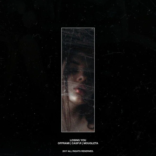 A woman with long hair and makeup looking into a cracked mirror with a black background.