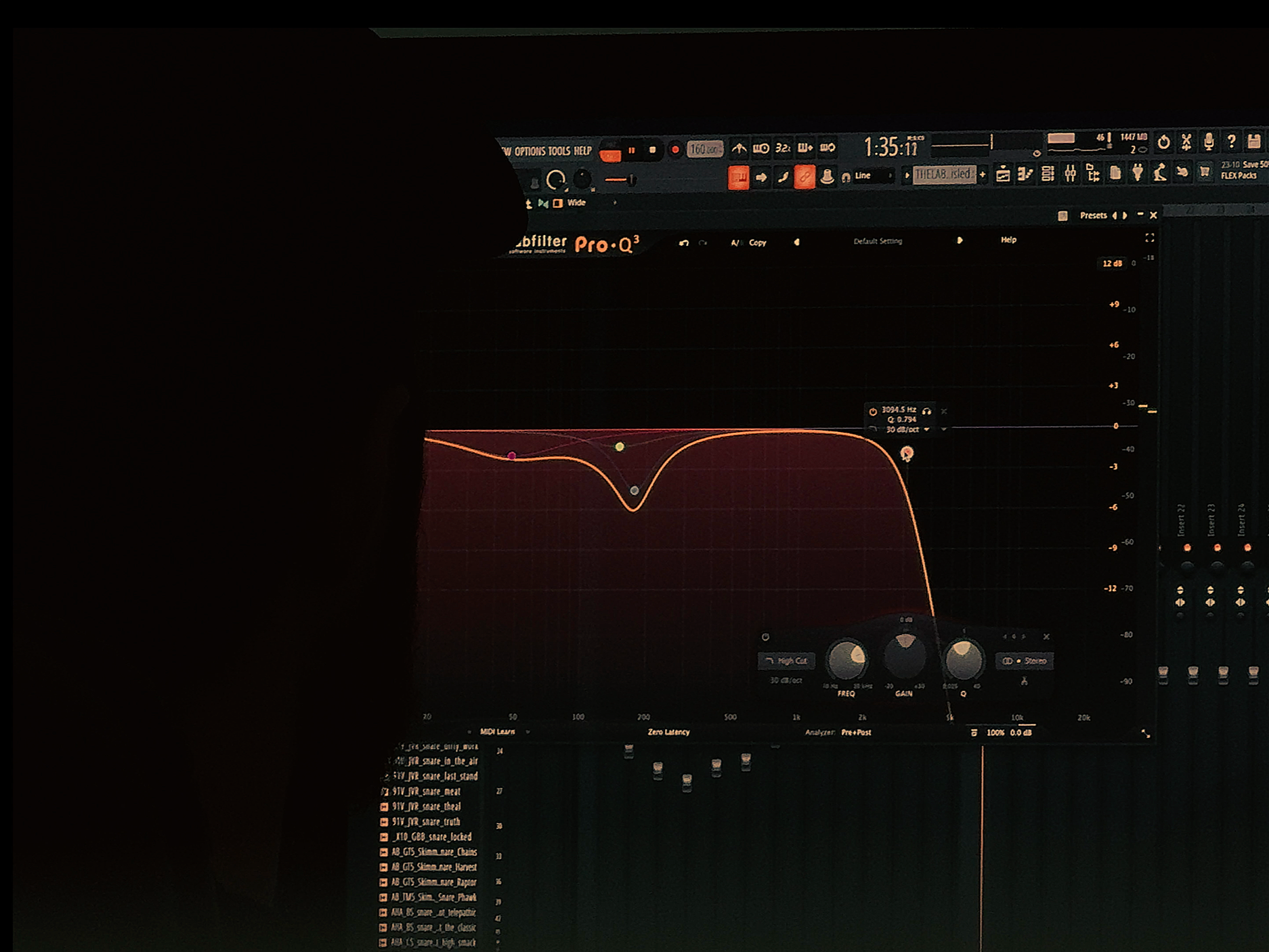 Computer screen in a dark room displaying music production software with an equalizer interface and various audio settings.