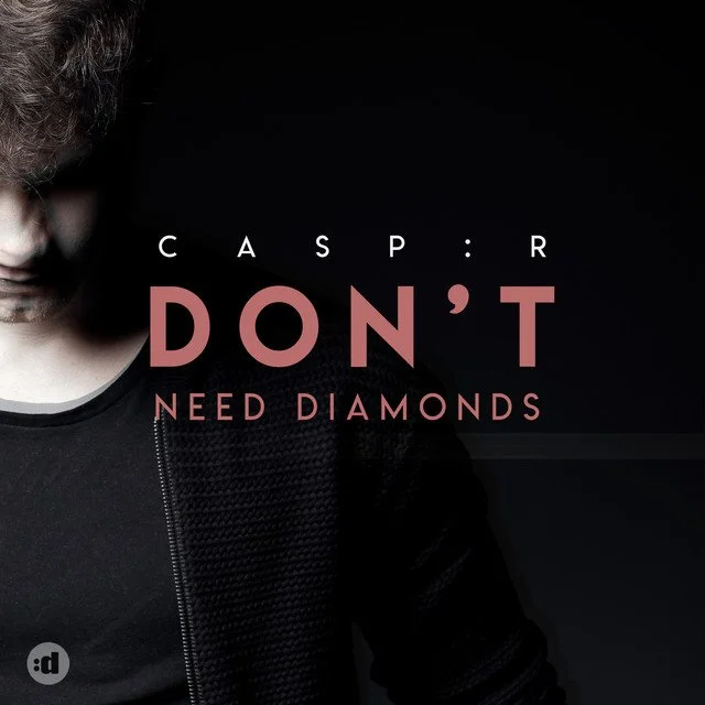 Partial image of a man with a beard wearing a black shirt and jacket, with text overlay that reads "Caspar DON'T Need Diamonds".