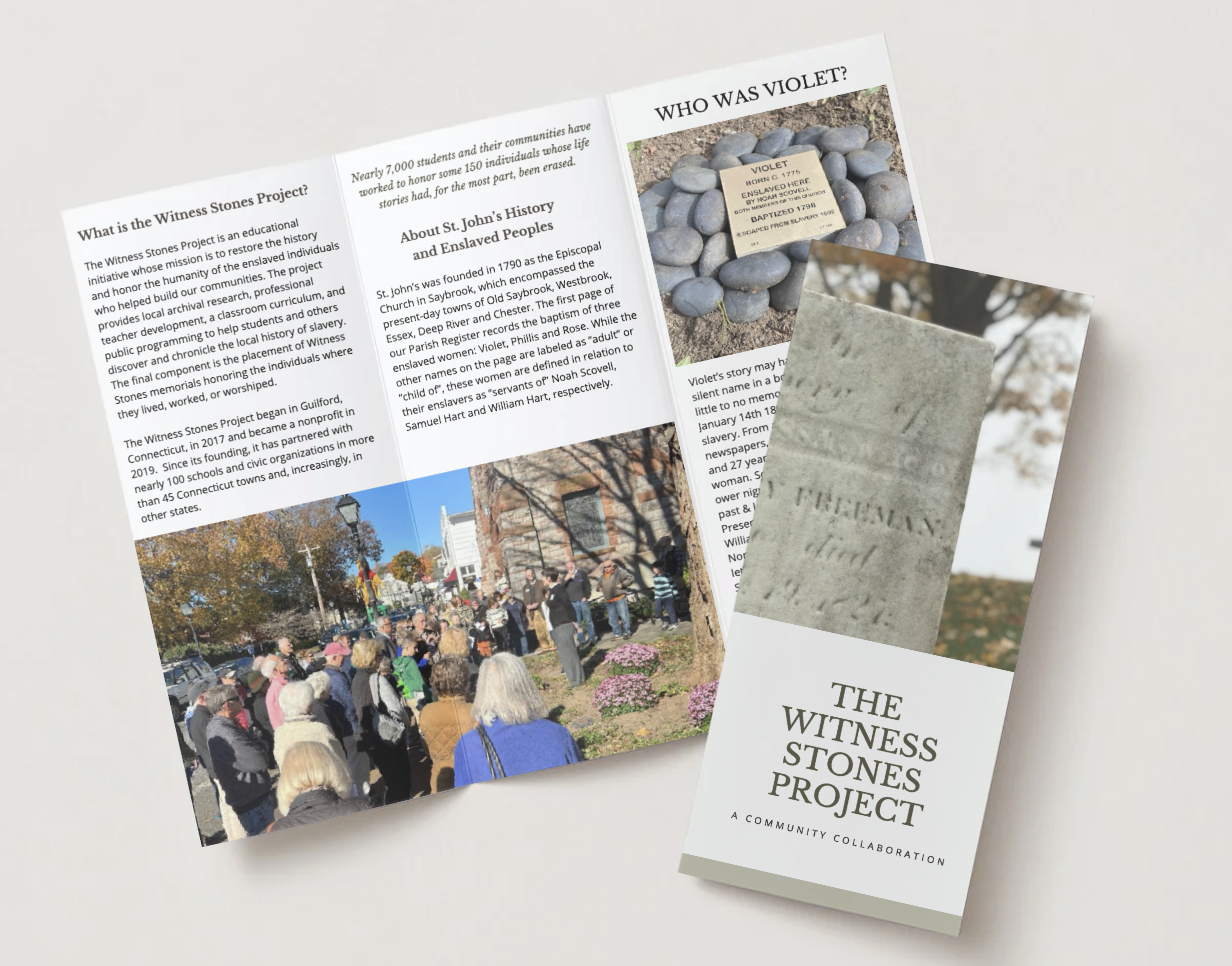 Brochure for The Witness Stones Project with a photo of a stone marker and an image of a stone monument, displayed open on a table with a crowd gathered outside.