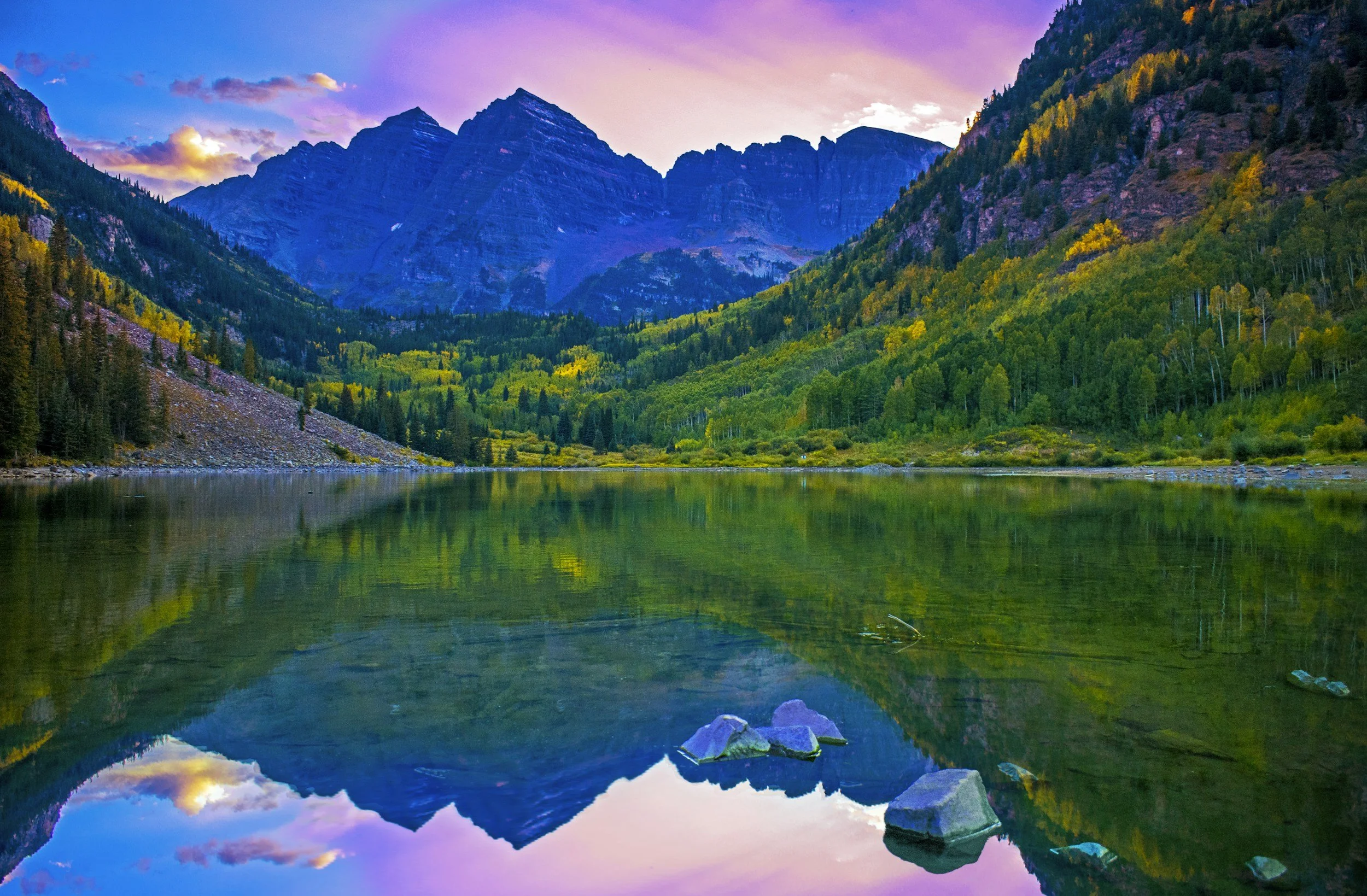 Serene Colorado mountain landscape with a lake reflecting a colorful sunset.