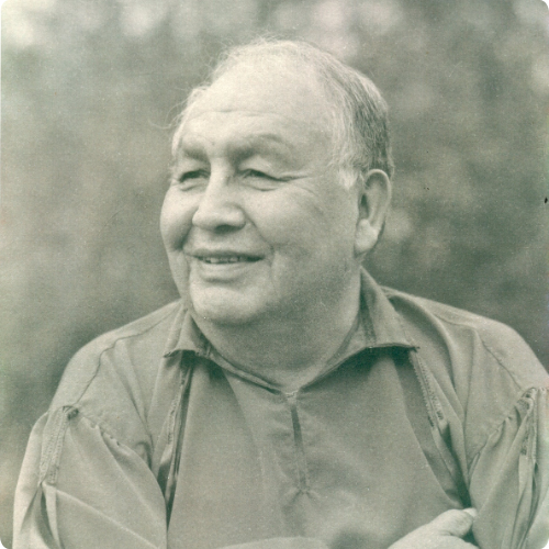Dr. Richard Little Bear, Commissioner, black-and-white portrait, smiling outdoors.