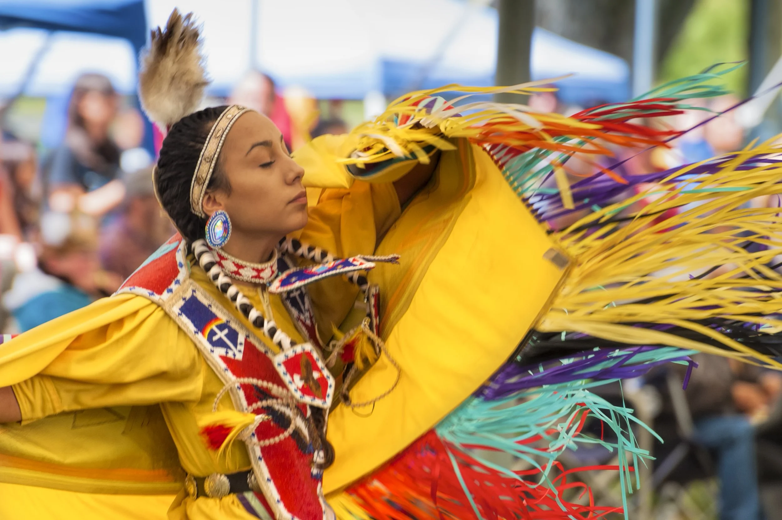 Native American woman dancing at a powwow in traditional regalia.