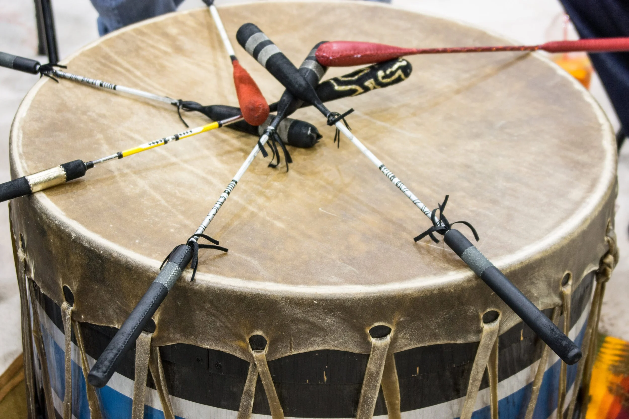 Traditional American Indian drum with leather drumhead and drumsticks resting on top.
