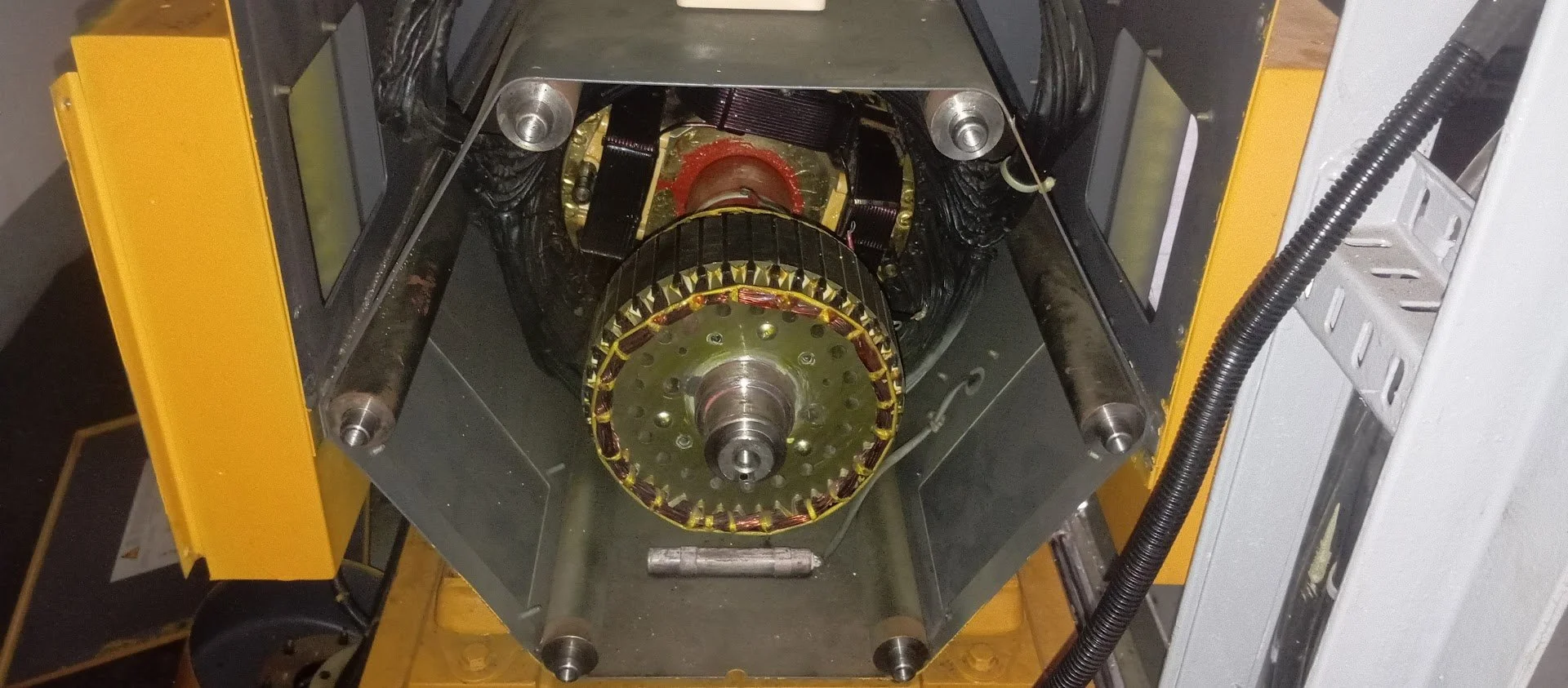 Imagem de um motor ou componente mecânico com partes metálicas, fios e estrutura de suporte, possivelmente para pesquisa ou fabricação de tecnologia avançada.