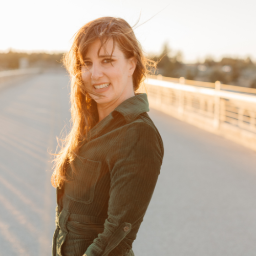 Young woman with long, wavy hair smiling and turning her head on a bridge during sunset