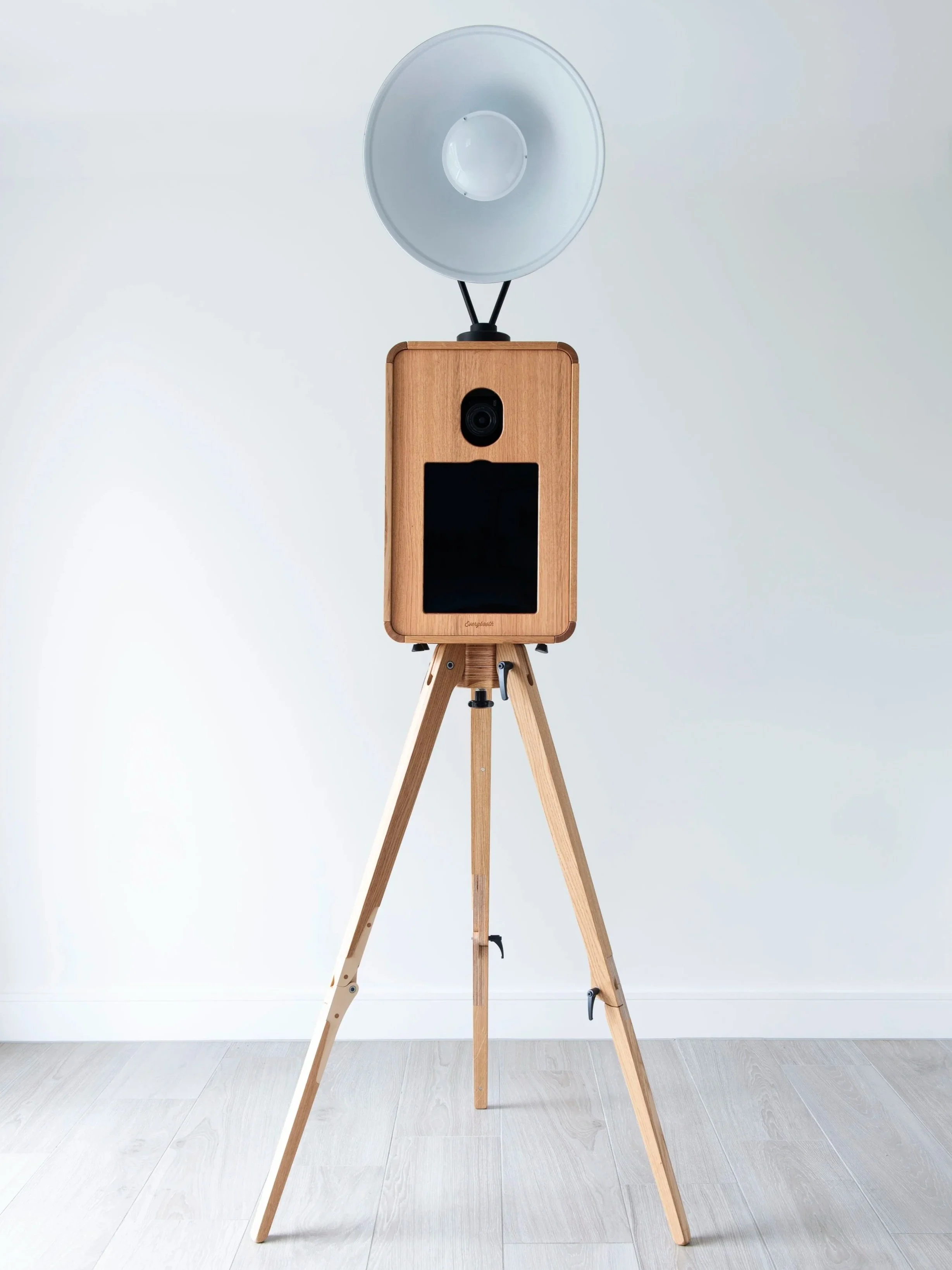 A wooden photo booth in Las Vegas with a large circular diffuser light mounted on top, set against a plain white wall