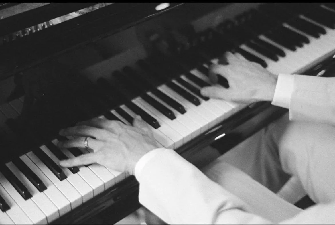 Close-up of hands playing a grand piano, black and white photo.