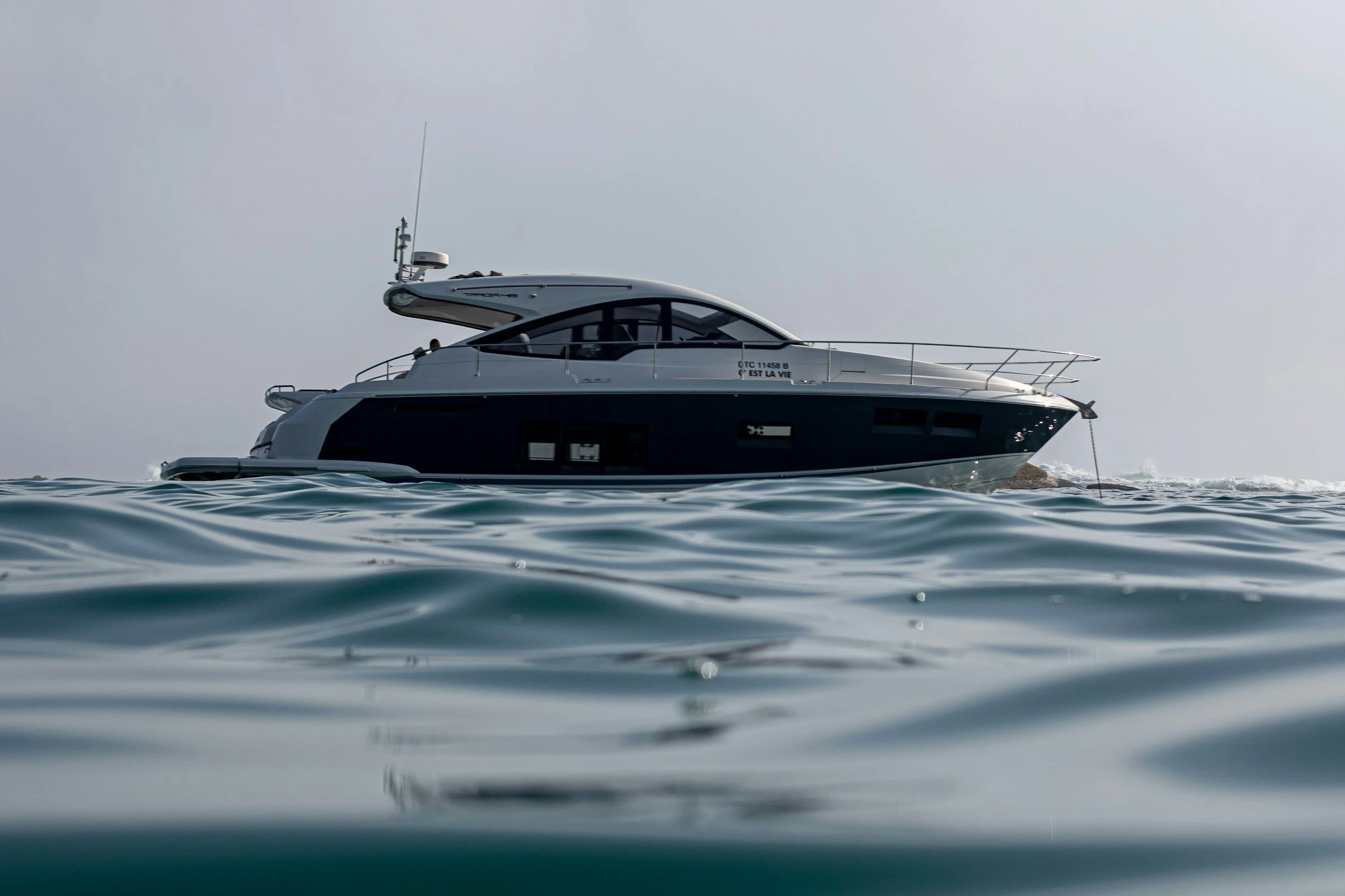 A modern yacht floating on the ocean with calm water surface and overcast sky