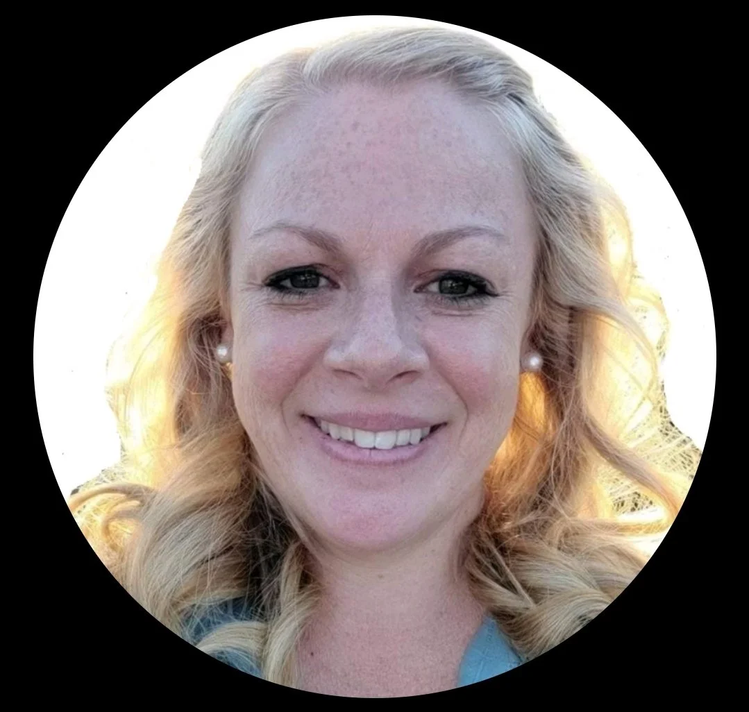 Close-up portrait of a smiling woman with blonde curly hair, wearing pearl earrings, outdoors with a bright background.