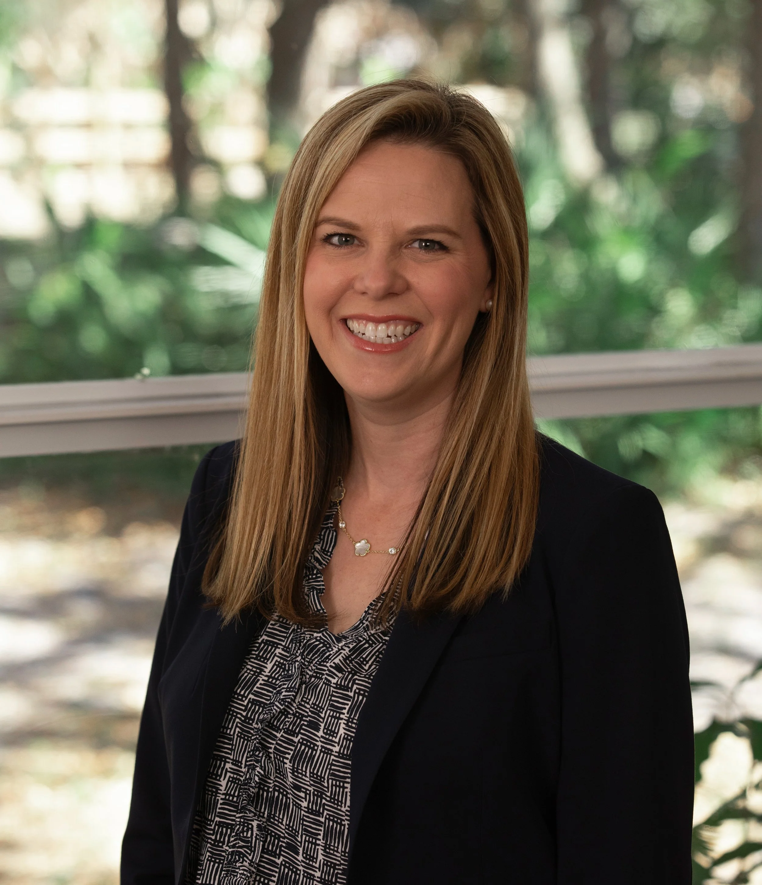 A woman with blond, wavy hair smiling in an indoor setting.