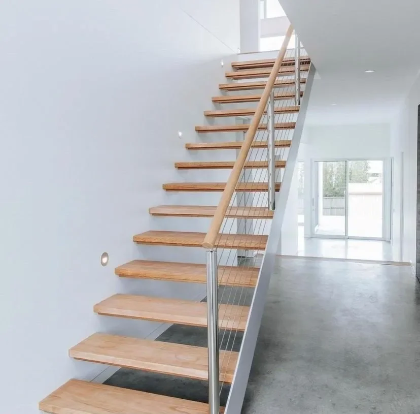 Modern wooden staircase with metal railing in a bright, minimalistic interior with large glass sliding doors.