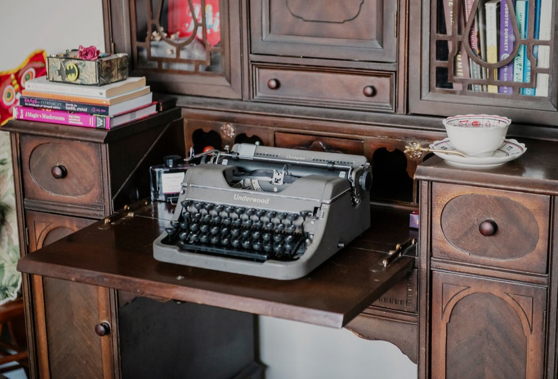Vintage Underwood typewriter on a wooden desk with books.