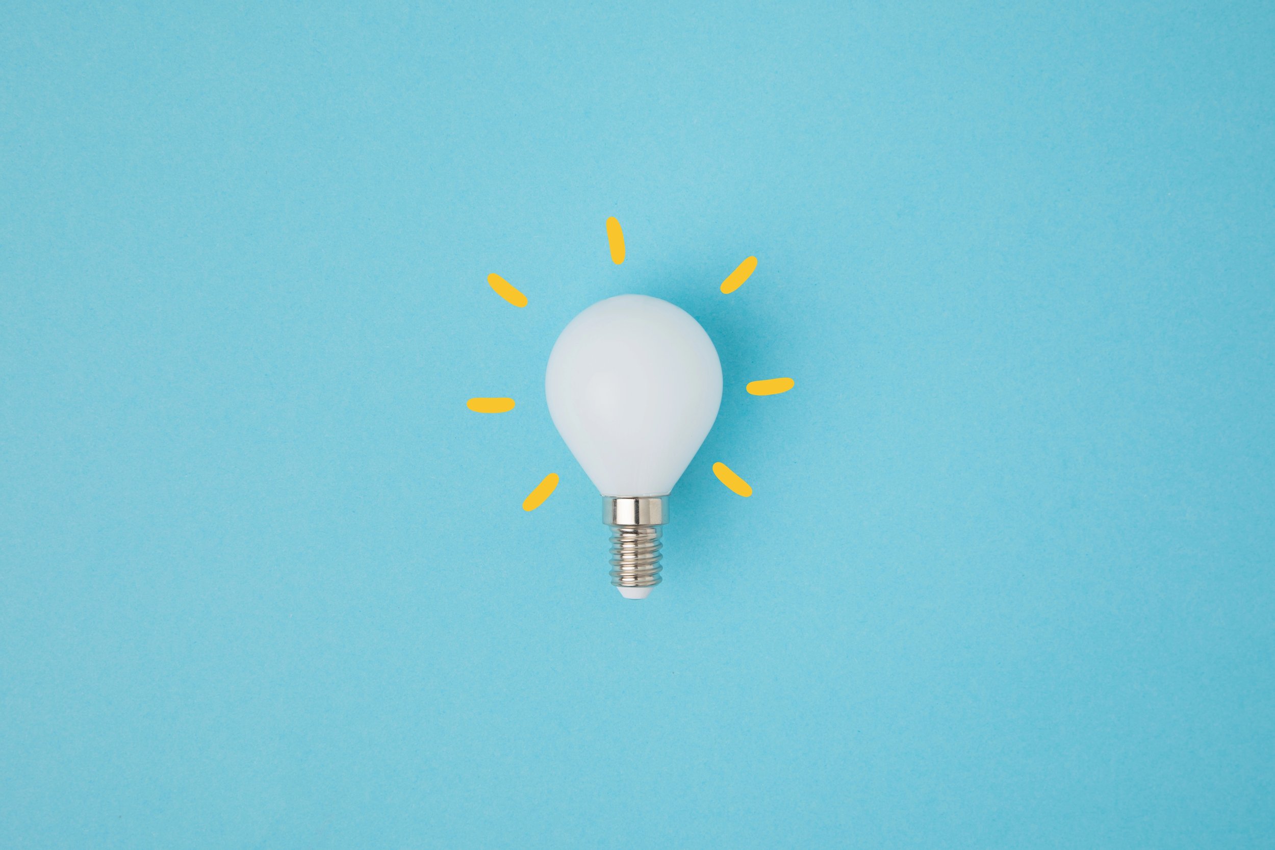 A light bulb with yellow lines around it on a blue background, resembling a glowing idea.