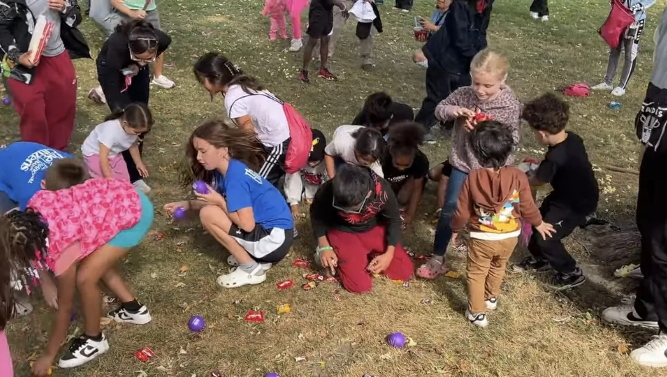 Group of children participating in collecting candy after hitting a piniata.