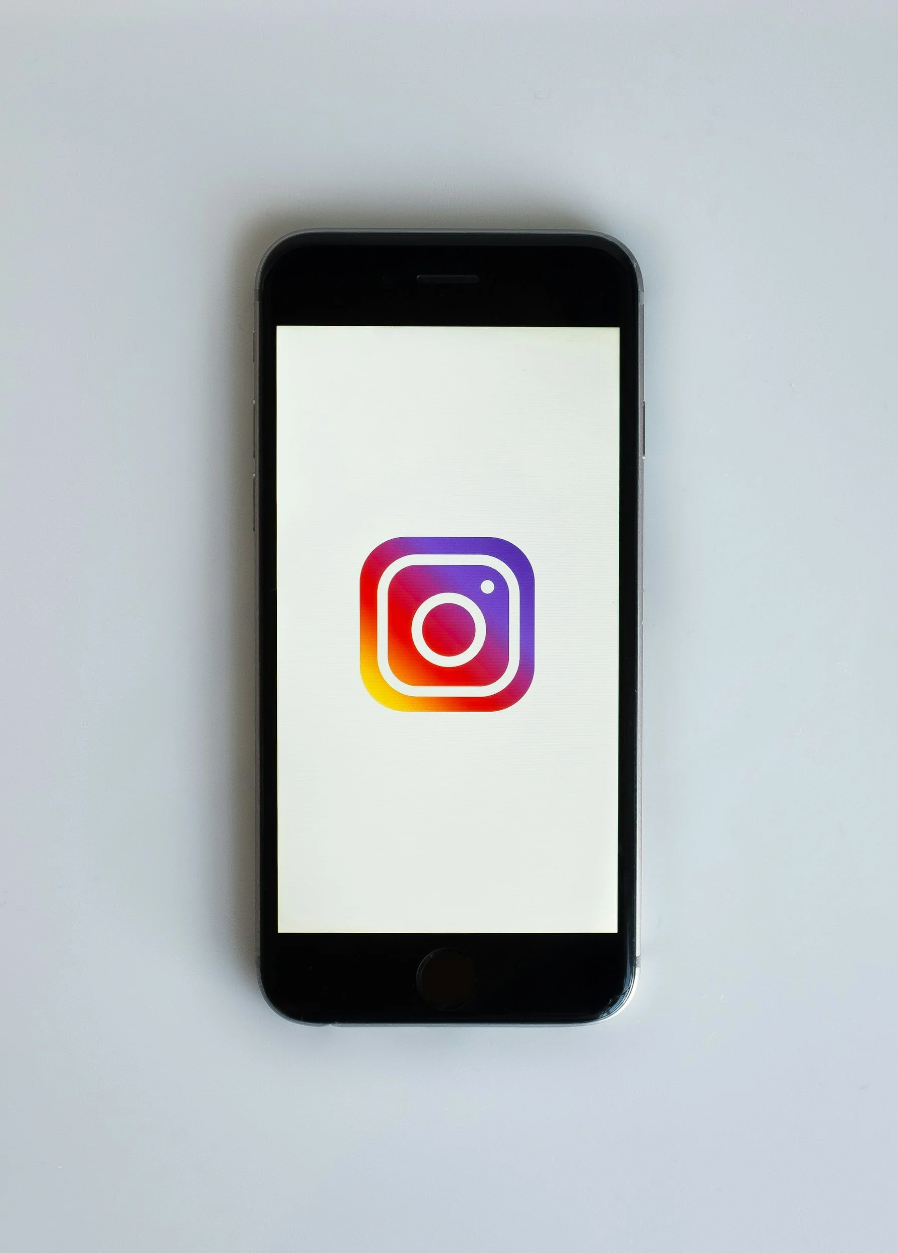 Smartphone displaying the Instagram app logo on a plain white background.